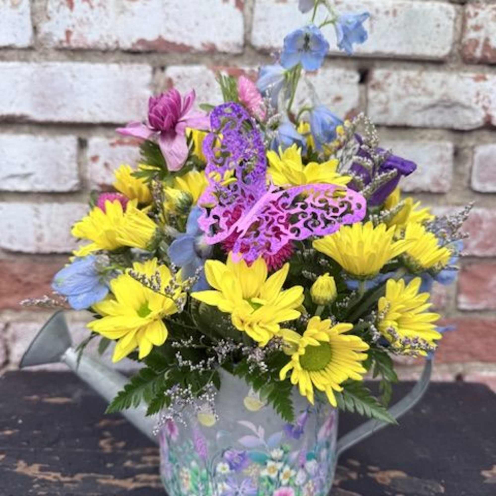 A bright cottage-style arrangement brimming with yellow daisy-like blooms and pops of
