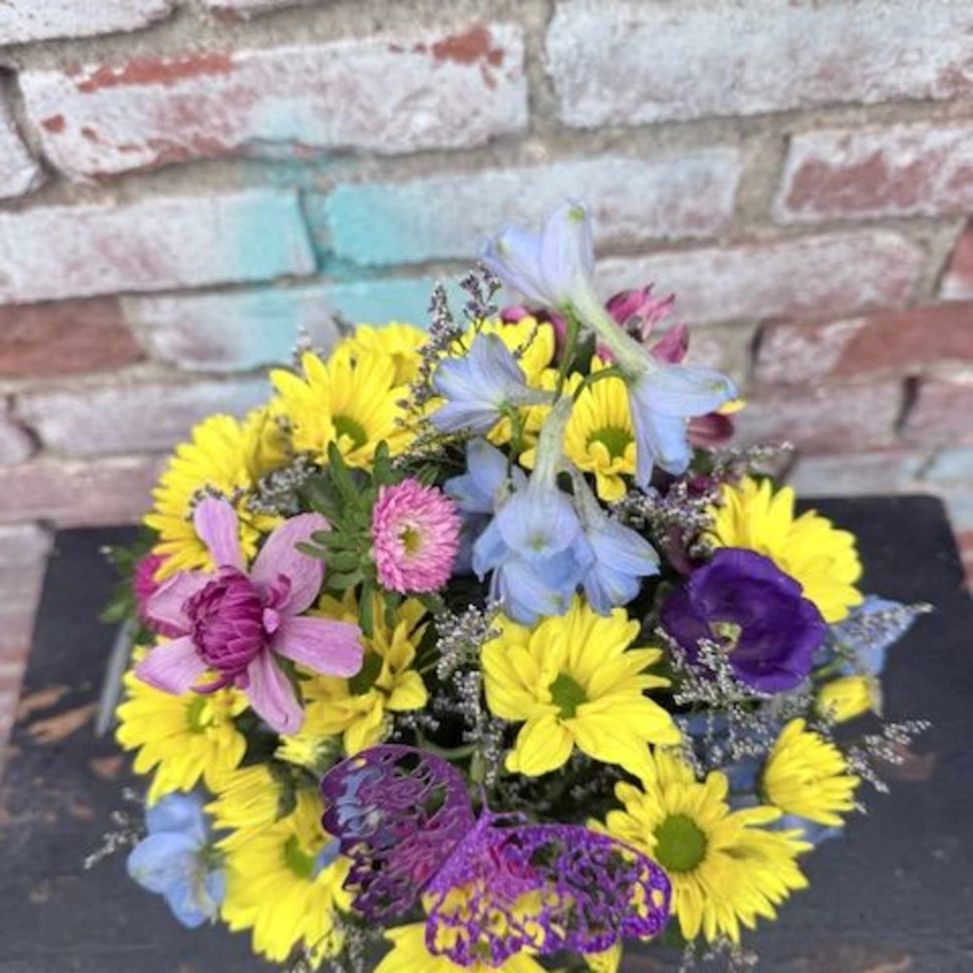 A bright cottage-style arrangement brimming with yellow daisy-like blooms and pops of