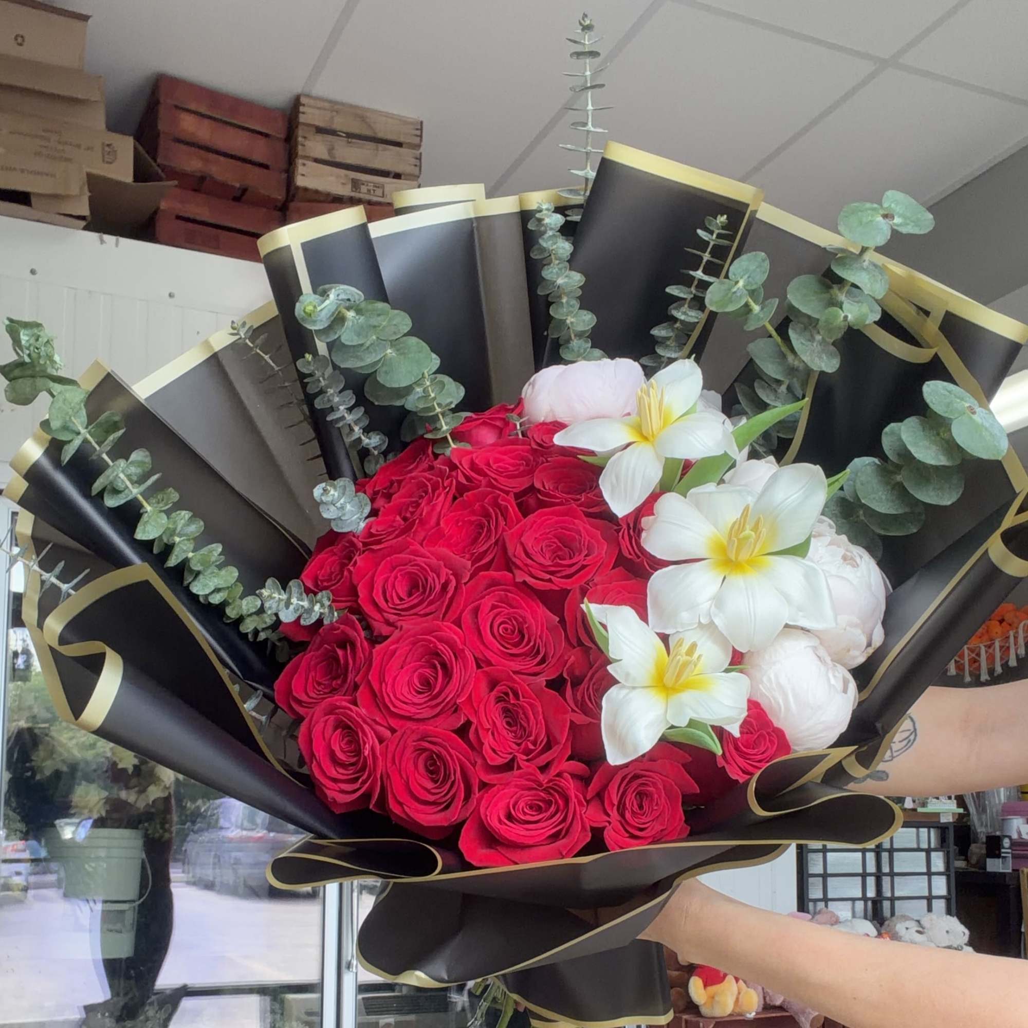 A dense cluster of vivid red roses anchors this premium bouquet, arranged