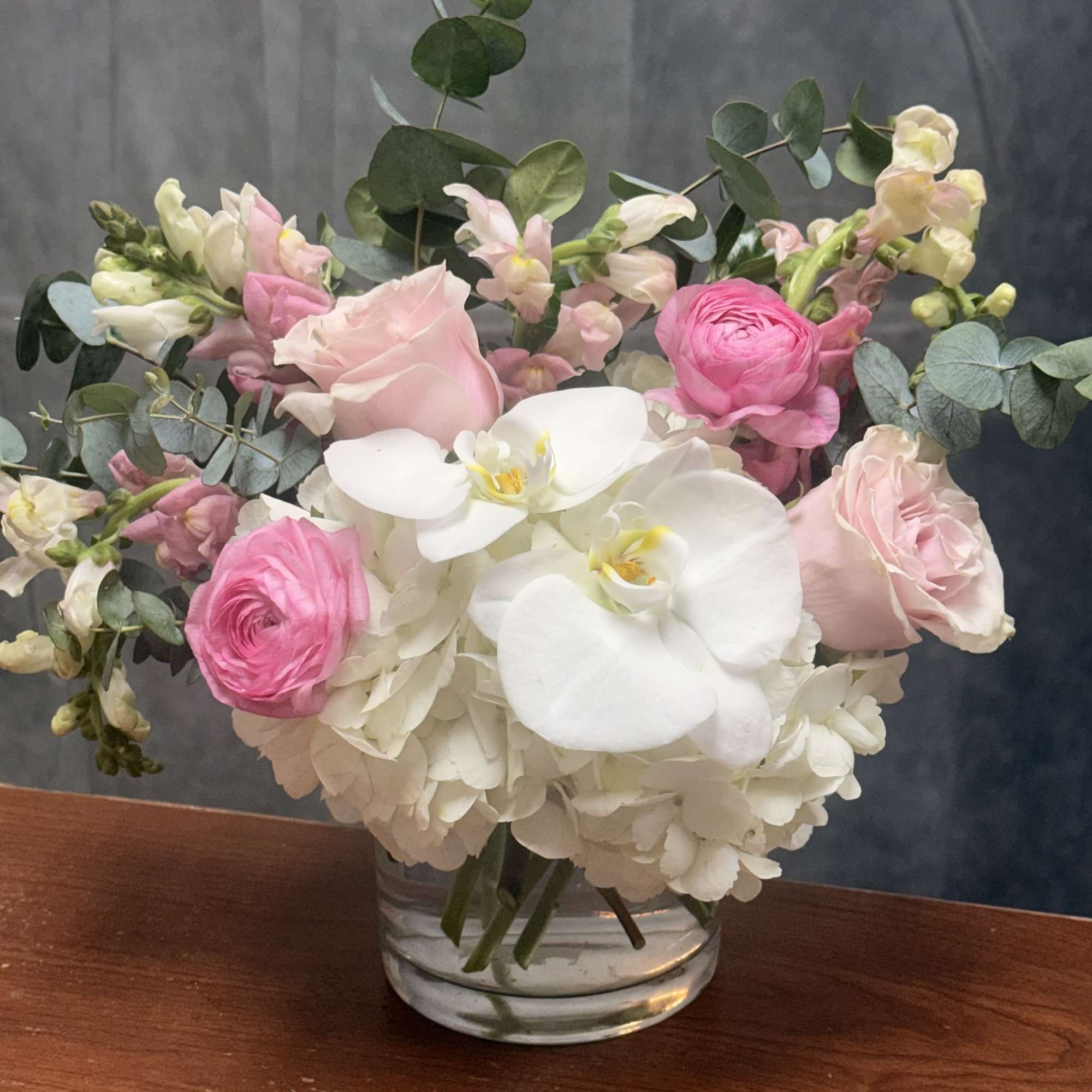 Pink and white flowers arranged in a clear glass vase