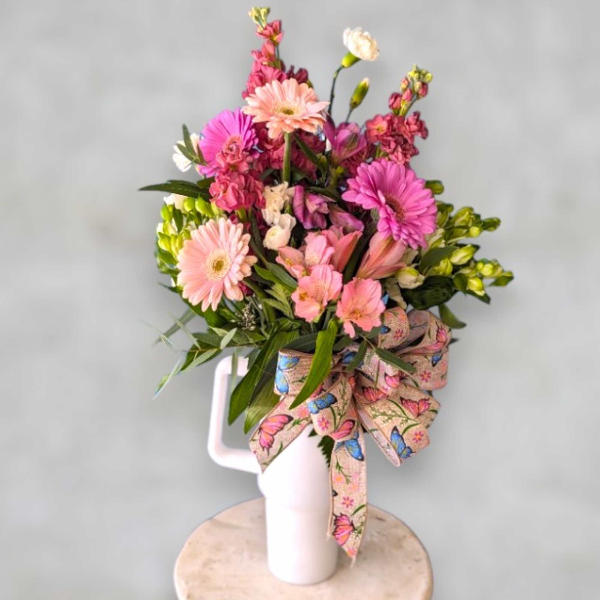 Pink and peach mixed bouquet in a white vase with a butterfly ribbon
