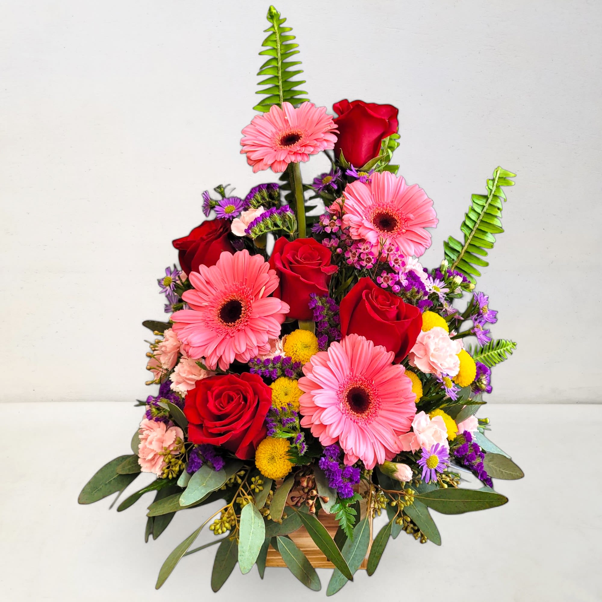A beautiful arrangement of flowers in a rustic wooden cube overflowing with