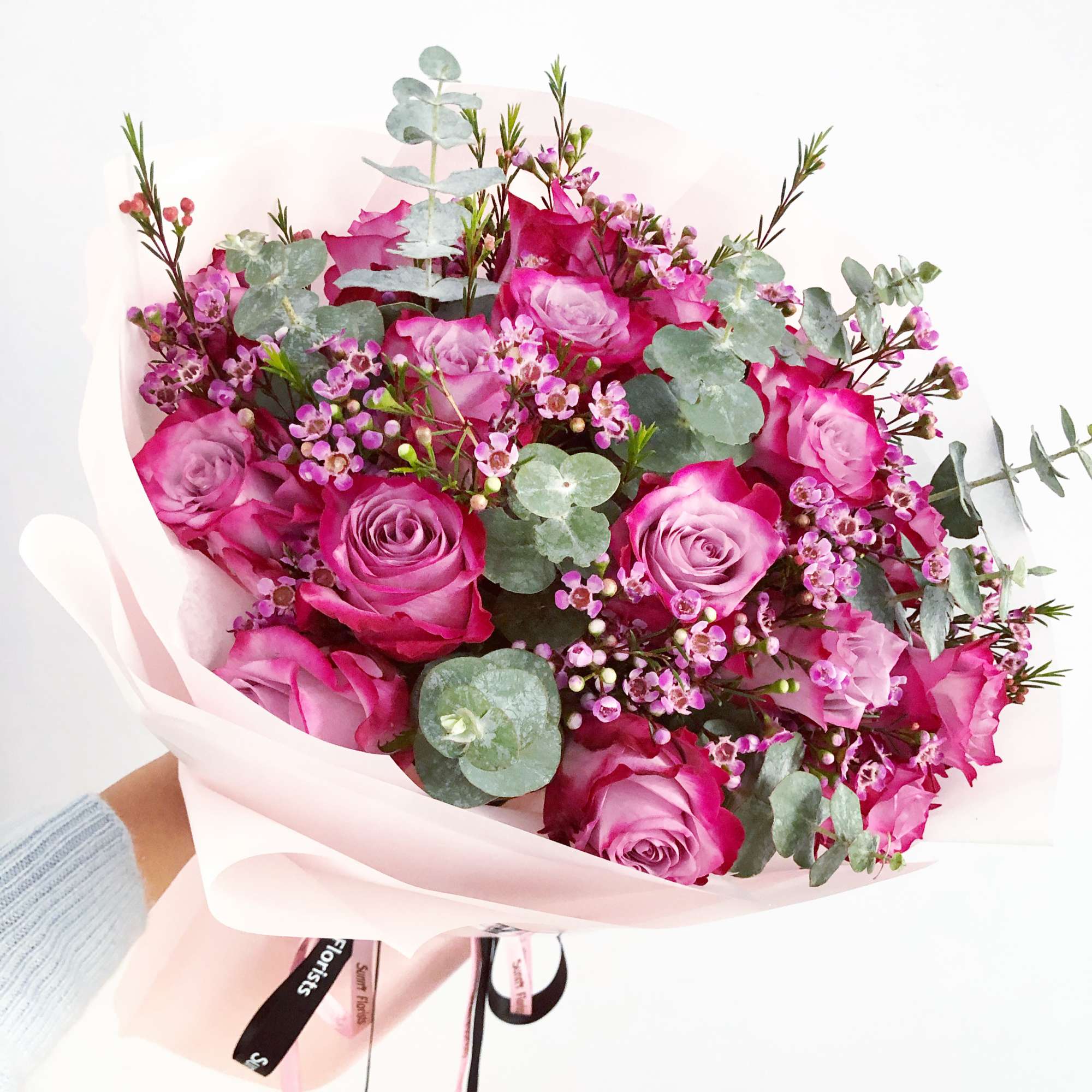 This arrangement features premium deep purple roses, accented with scented wax flowers