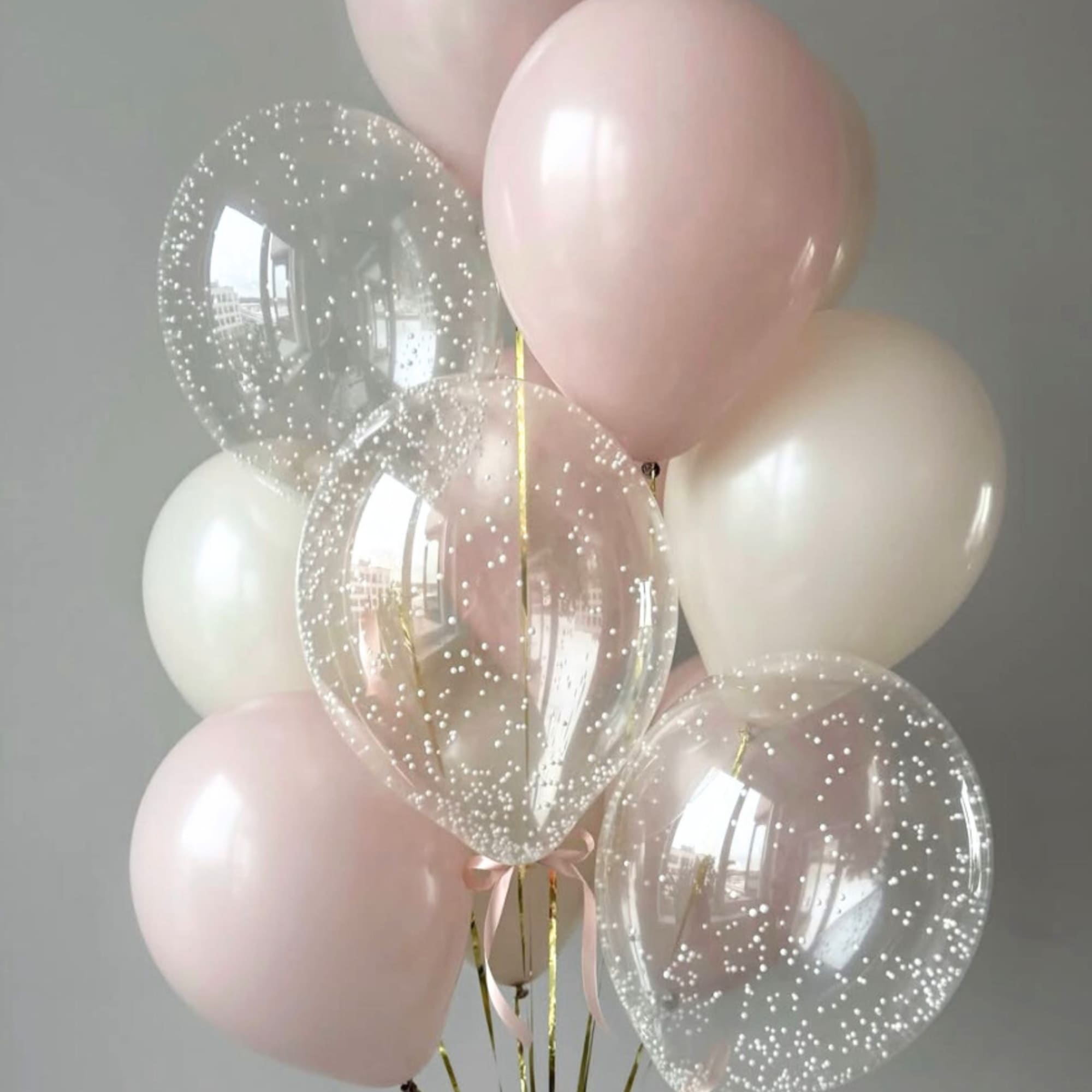 Cluster of pale pink and clear confetti balloons with gold ribbons