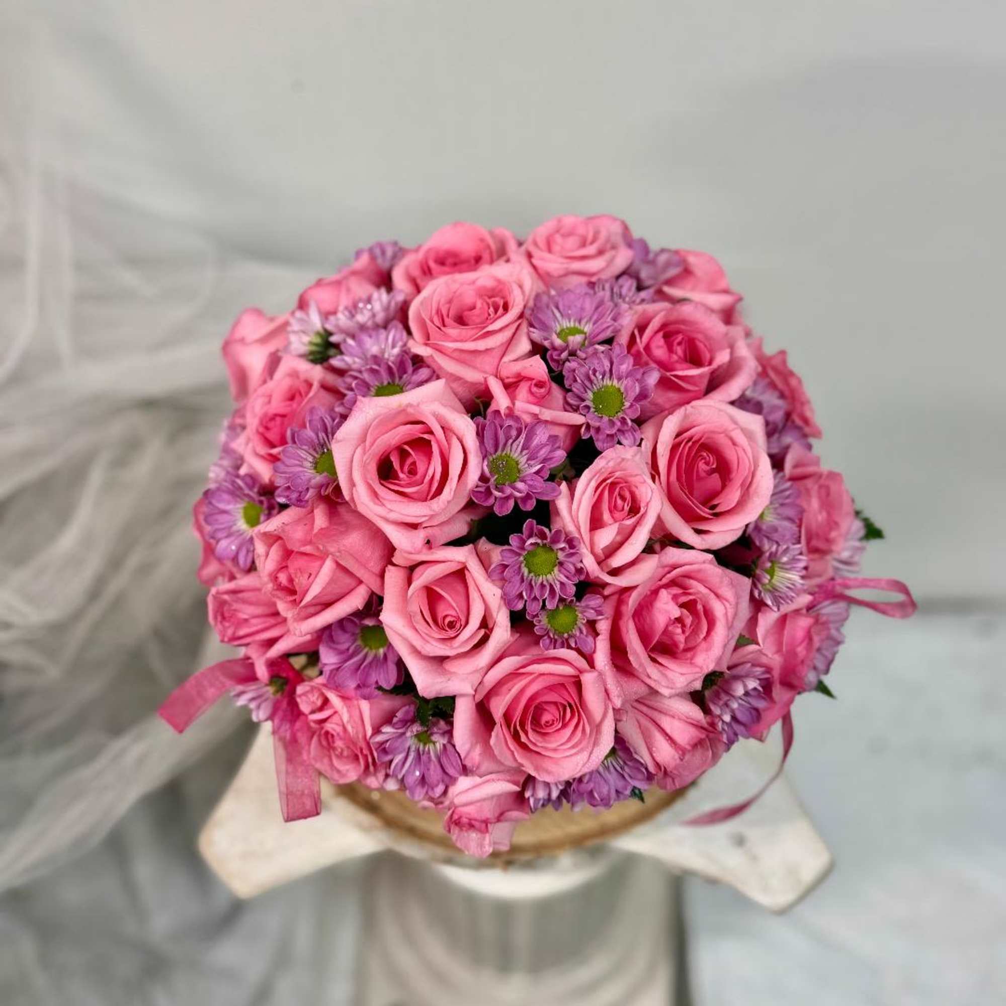 Pink rose bouquet with small purple daisies in a round arrangement