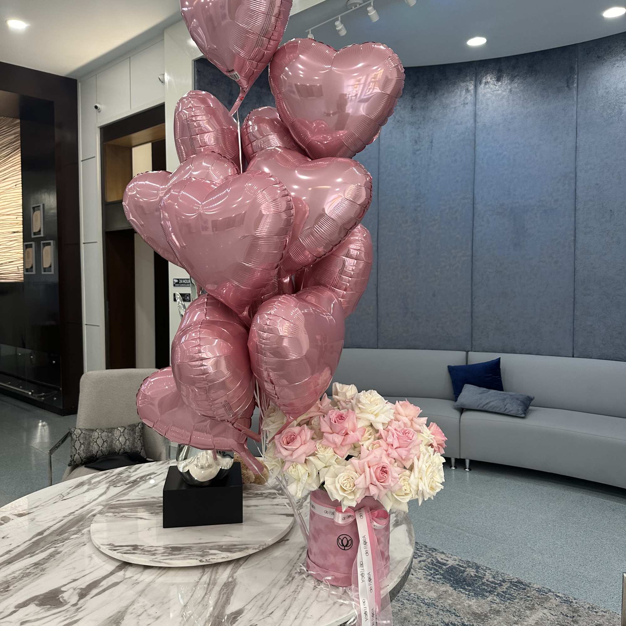 Pink heart balloons beside a bouquet of pink and white roses