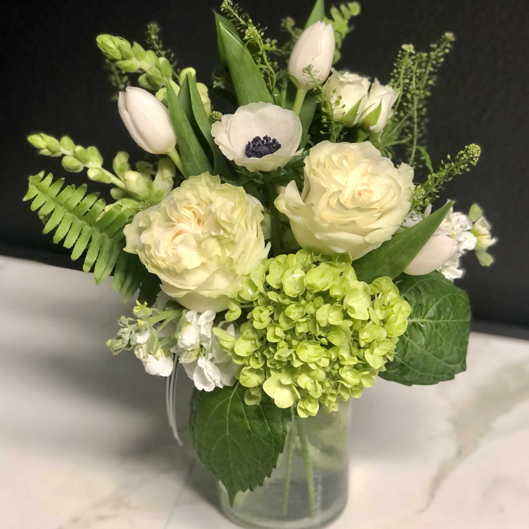 White and pale green floral arrangement in a glass vase