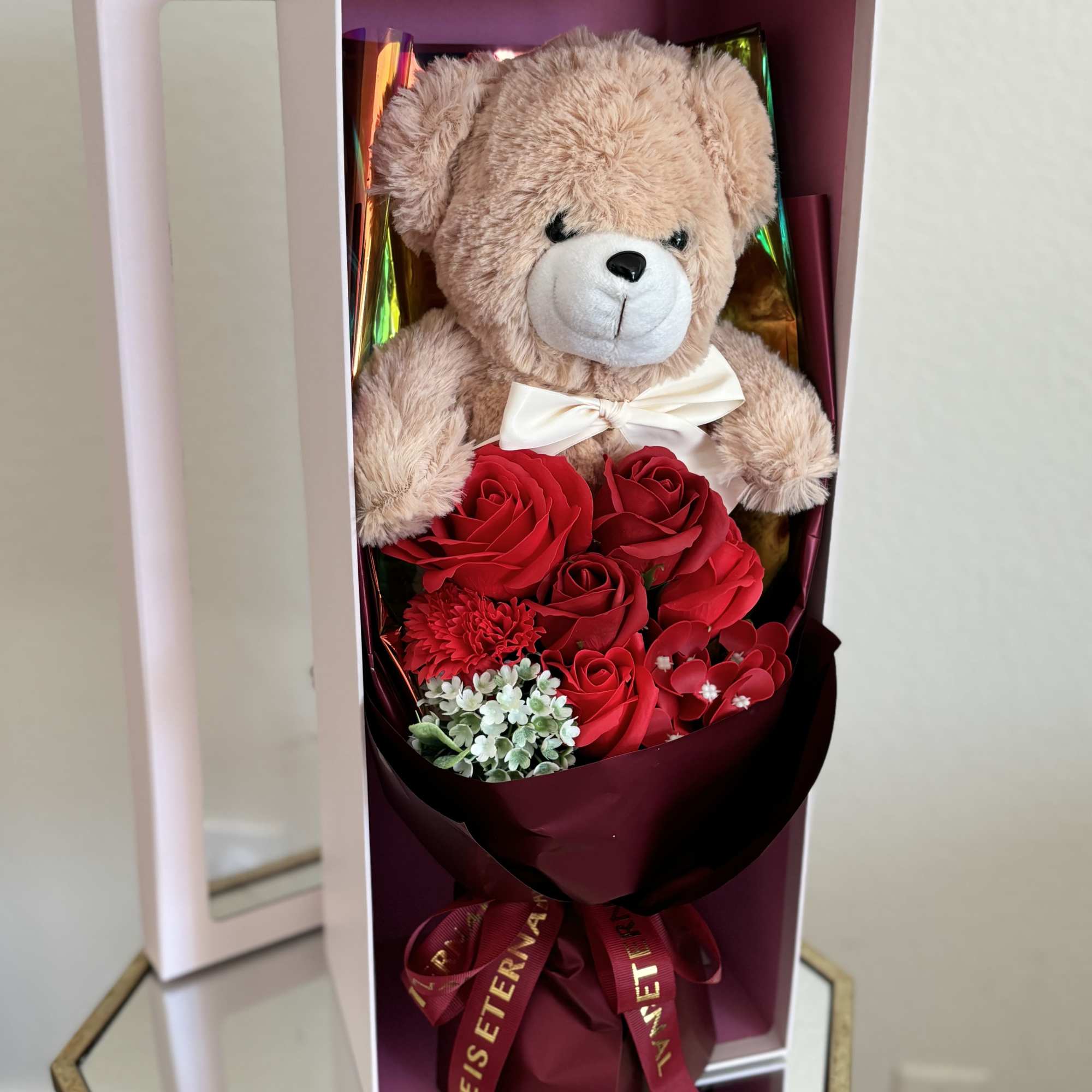 Teddy bear in a box with red roses and a ribbon bow