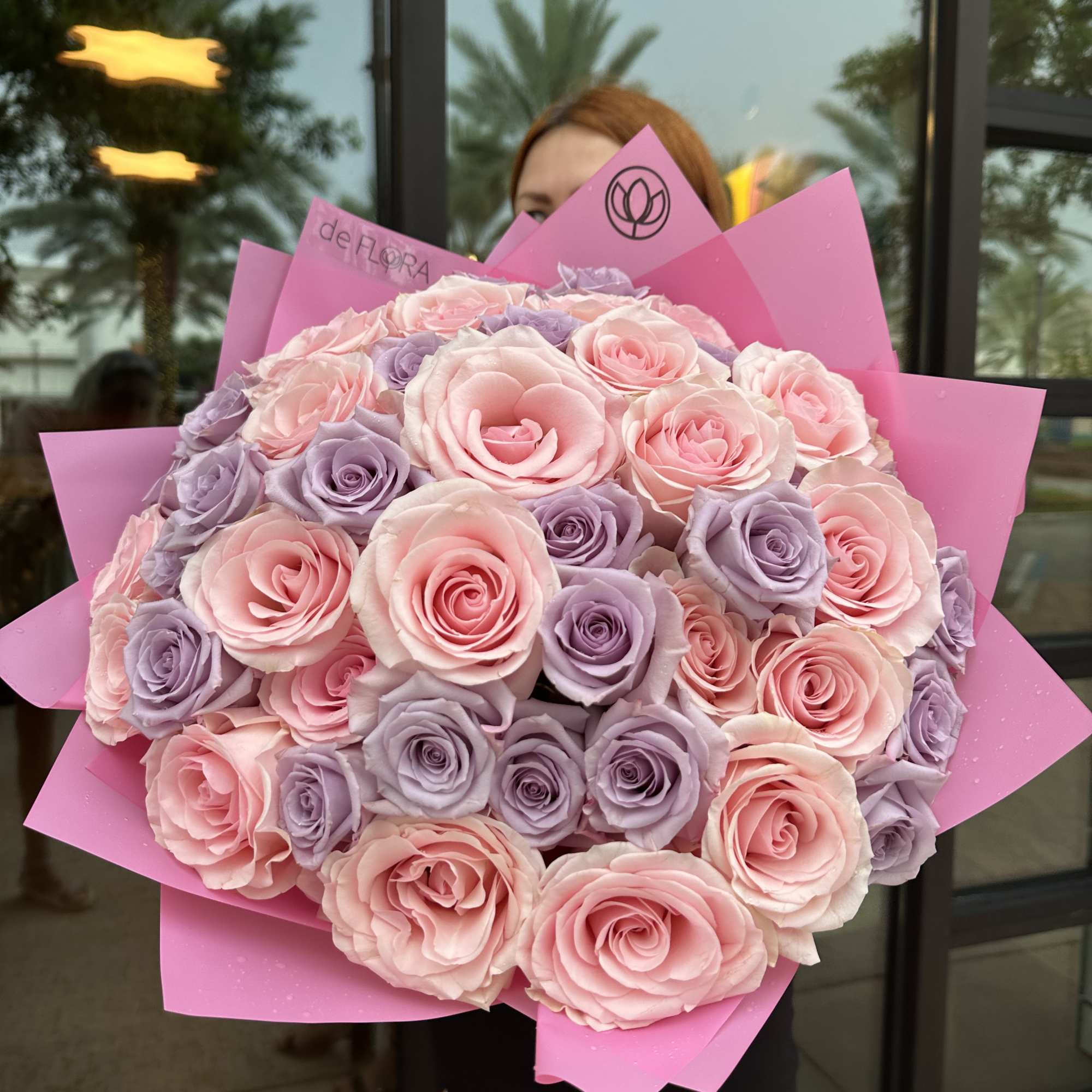 Large bouquet of pink and lavender roses wrapped in bright pink paper