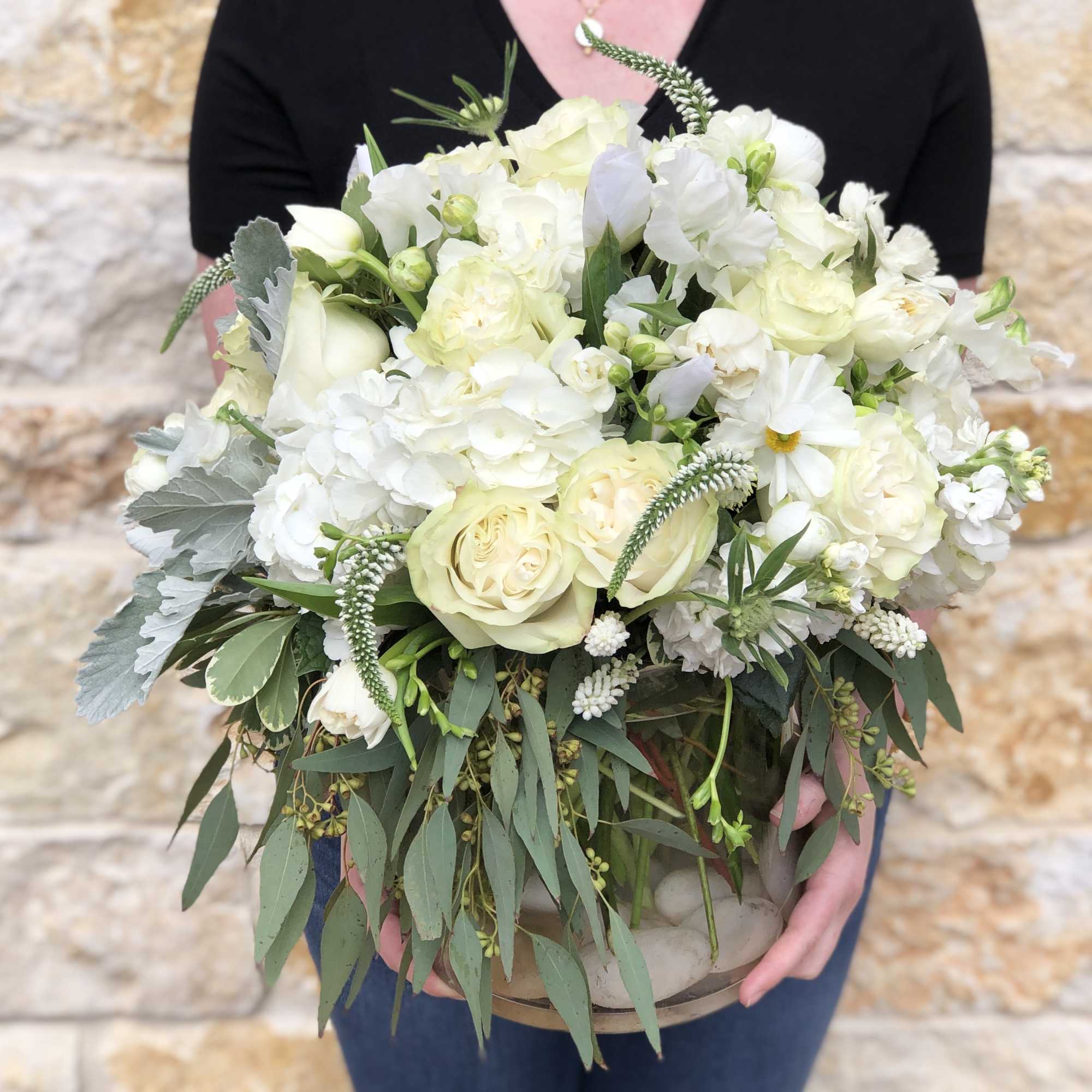 White floral bouquet with roses and daisies in a low container