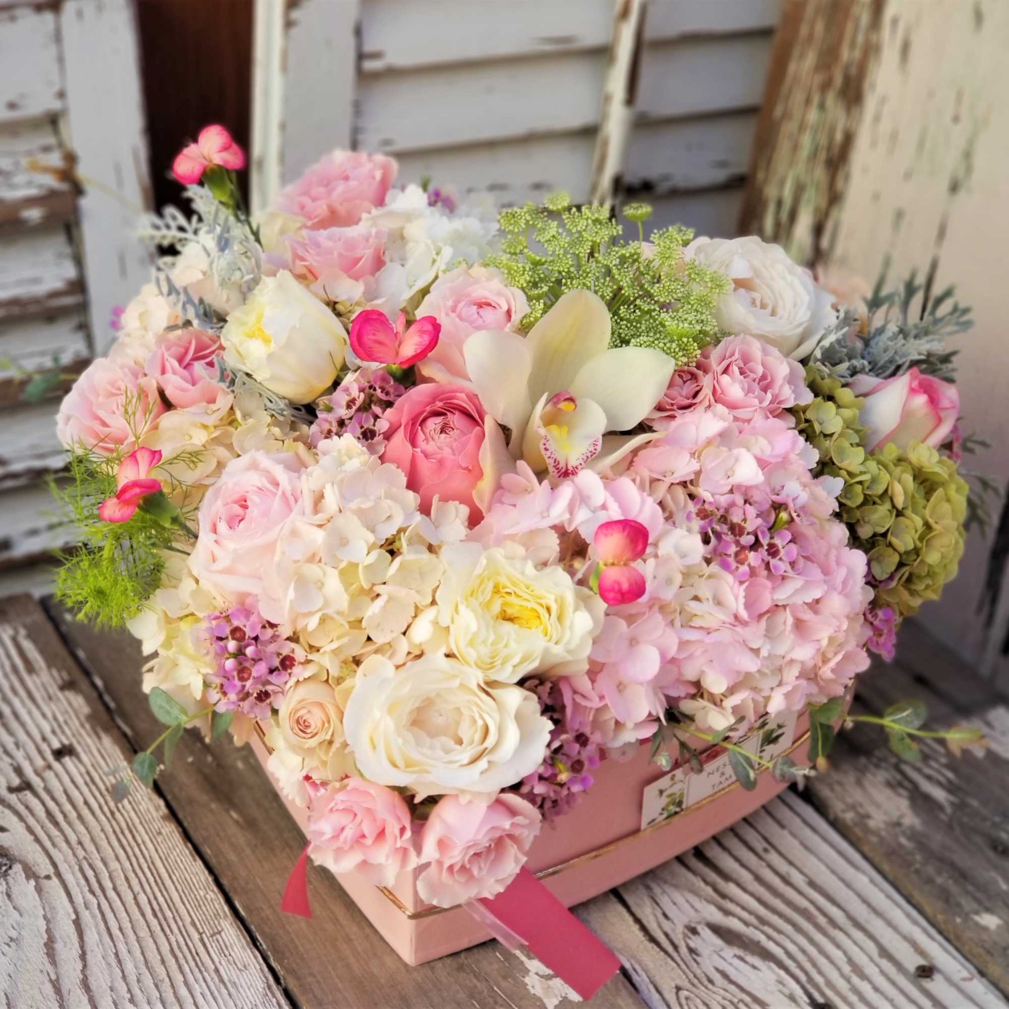 Pink and white mixed flower arrangement in a pink box