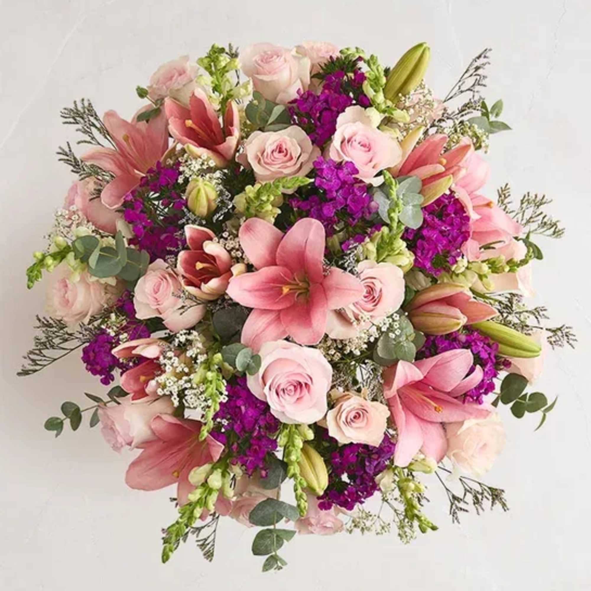 Soft pink lilies and pale blush roses take center stage in this