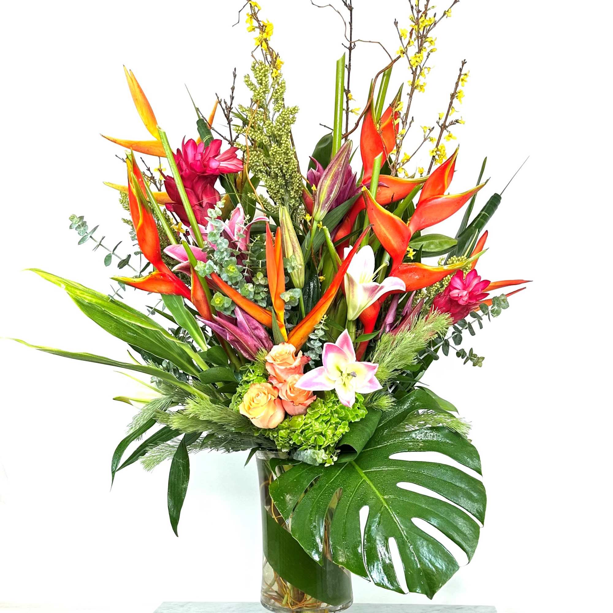 Tropical flower arrangement in a glass vase with orange heliconia and lilies