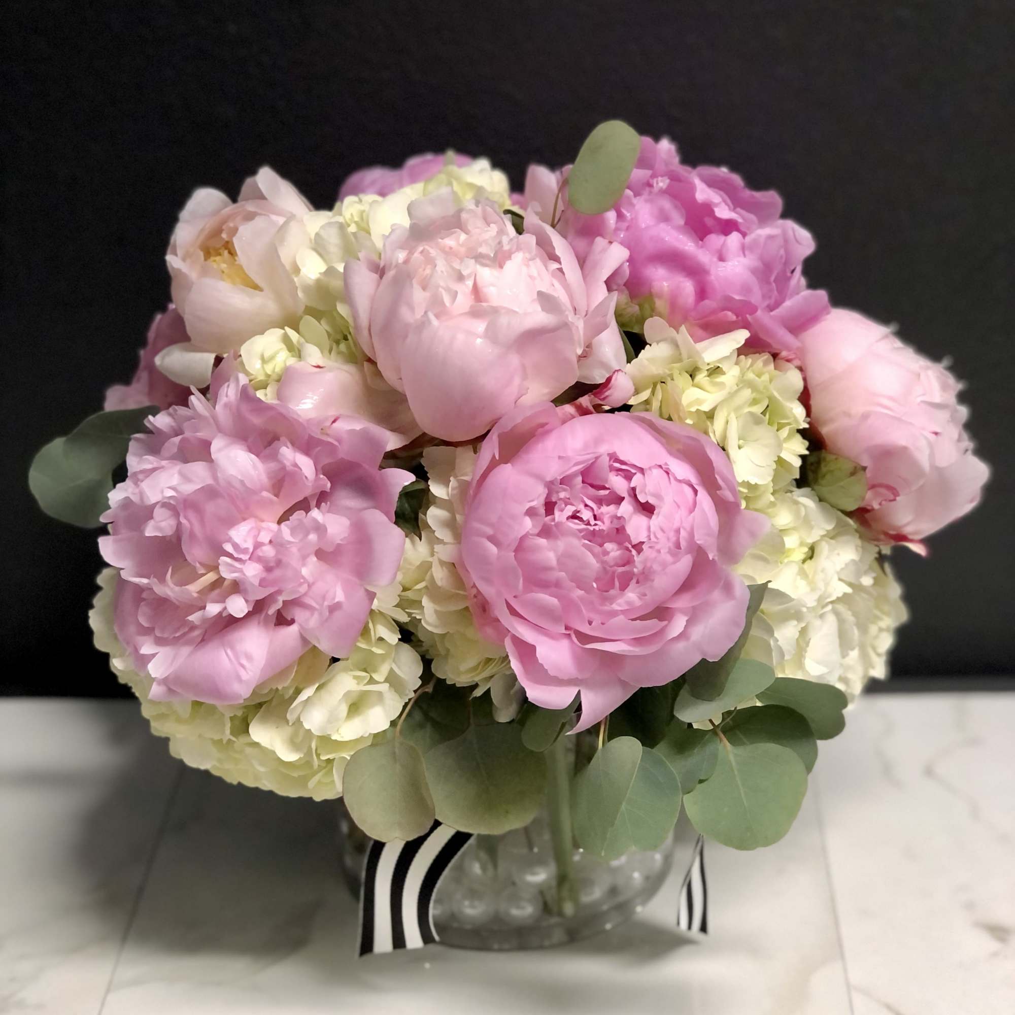 Pink peonies and pale hydrangeas in a glass vase
