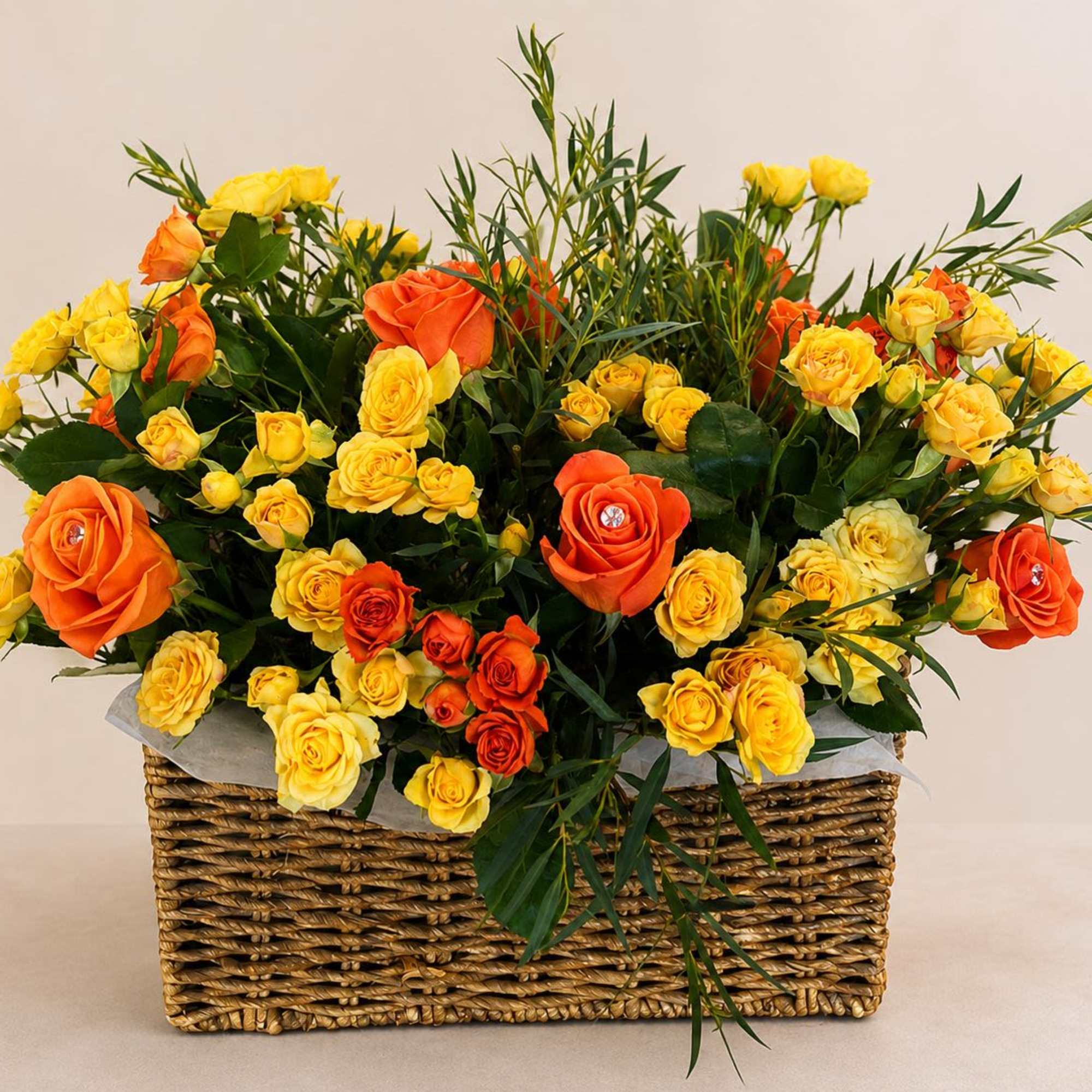 A charming basket arrangement combining mini yellow and orange roses, enhanced with