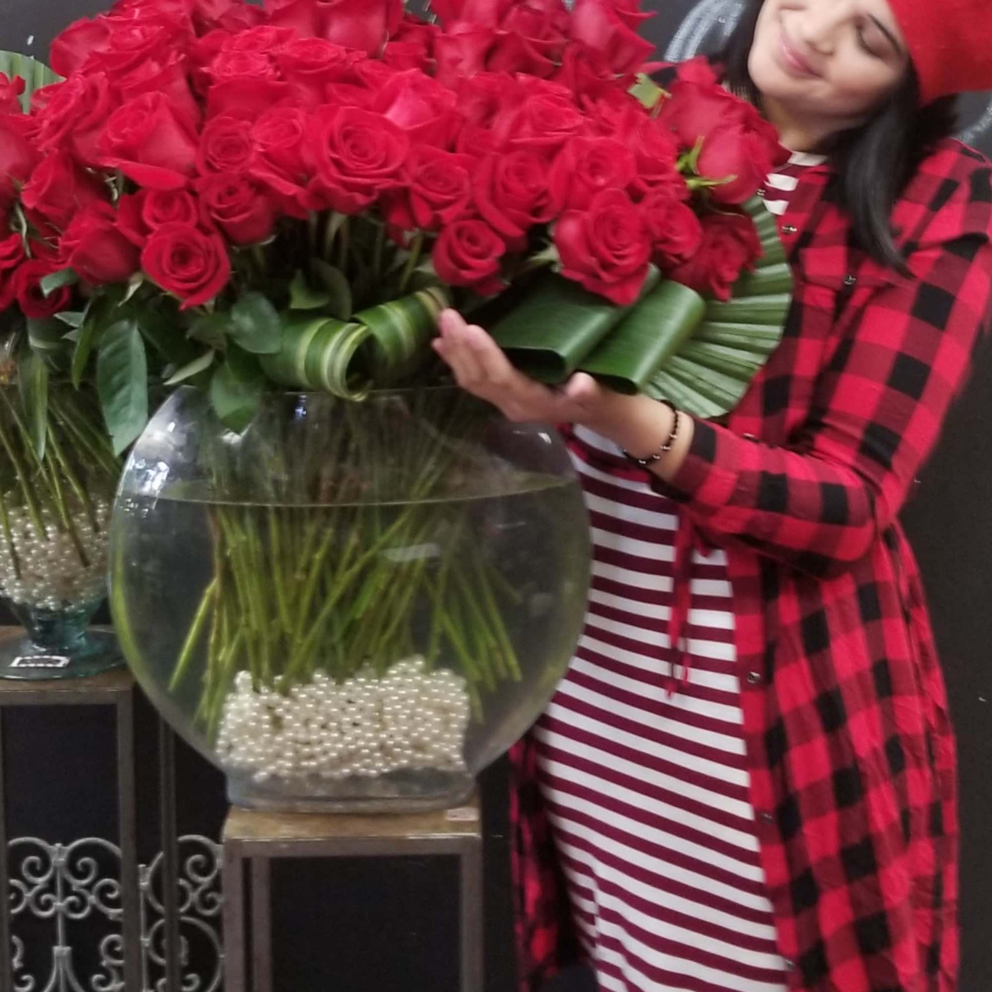 Woman holding a large bouquet of red roses in a glass vase