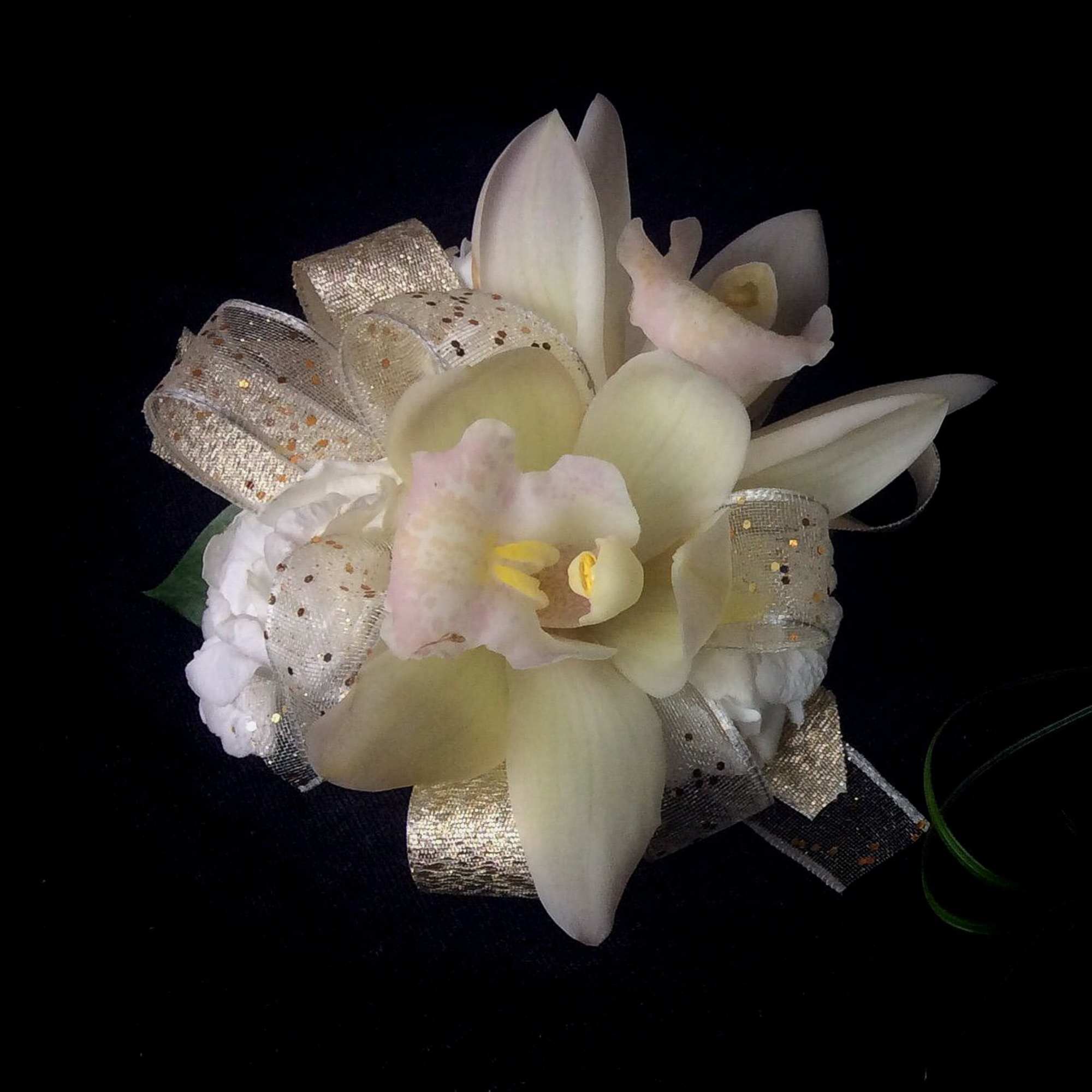 White orchid corsage with silver ribbon on a black background
