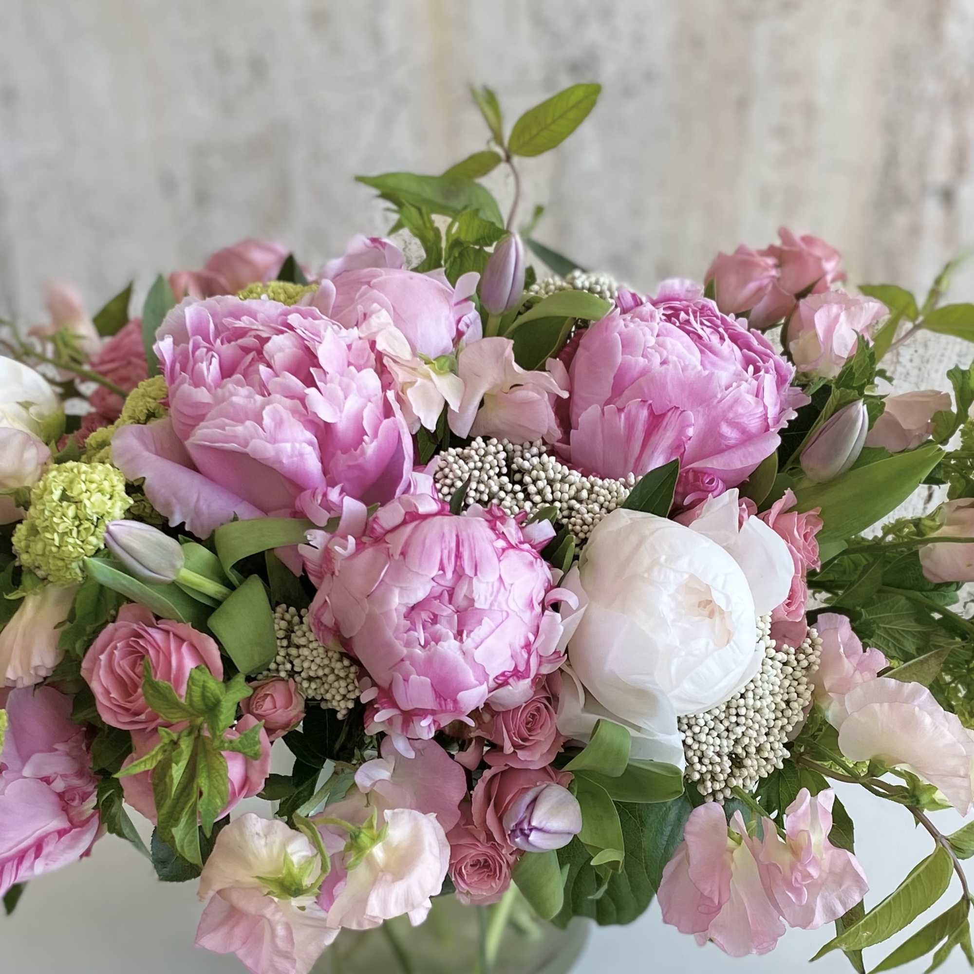 Pink peonies and roses arranged in a glass vase