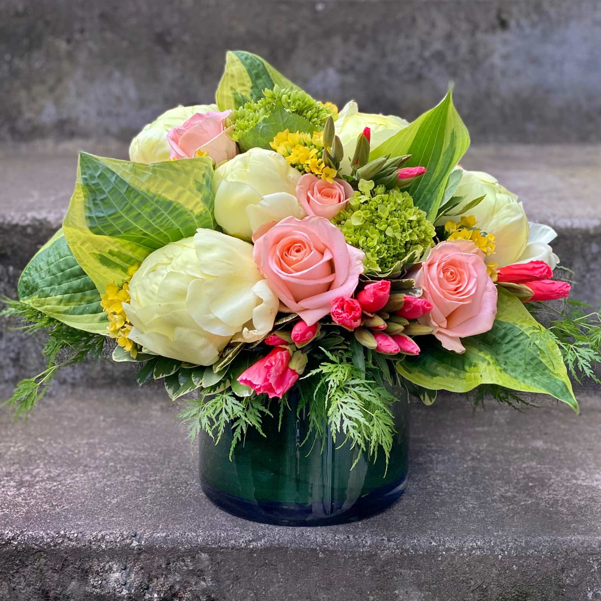 Pink roses and white blooms arranged in a dark glass vase