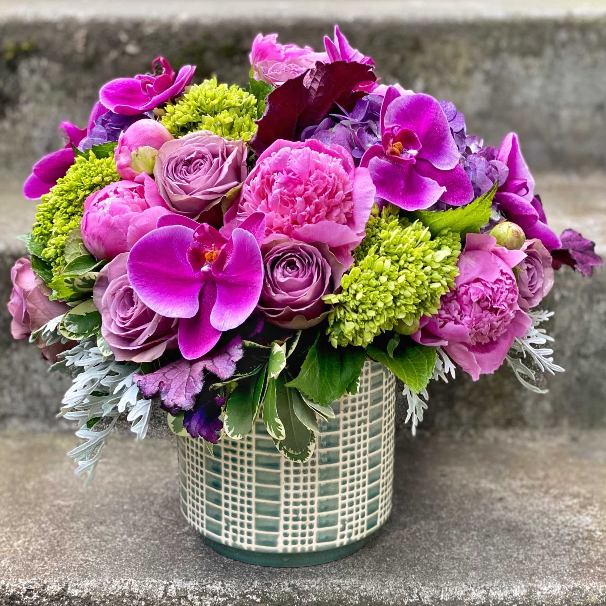 Pink and purple floral arrangement in a patterned ceramic vase