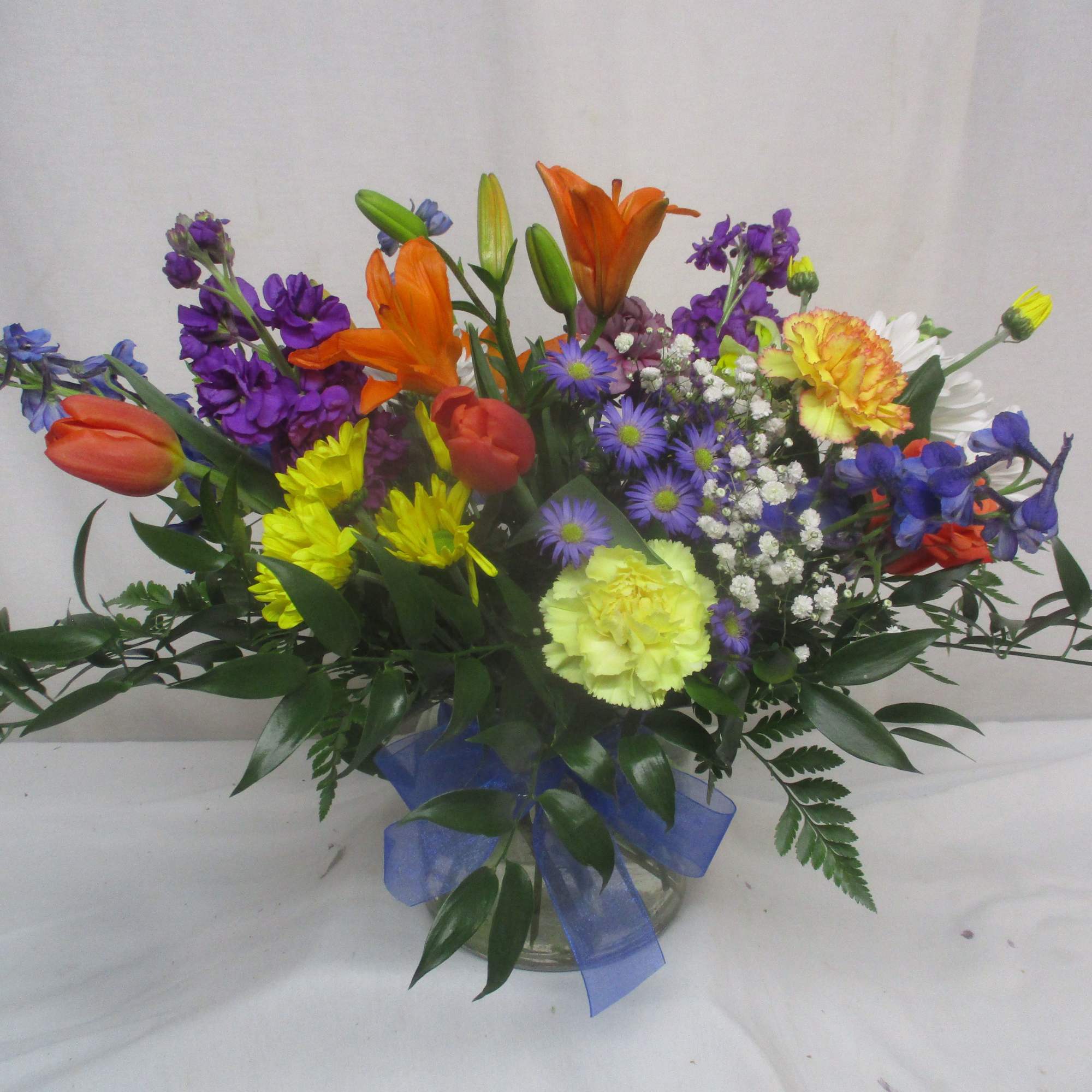 A lively cascade of orange tulips and lilies greets the eye first