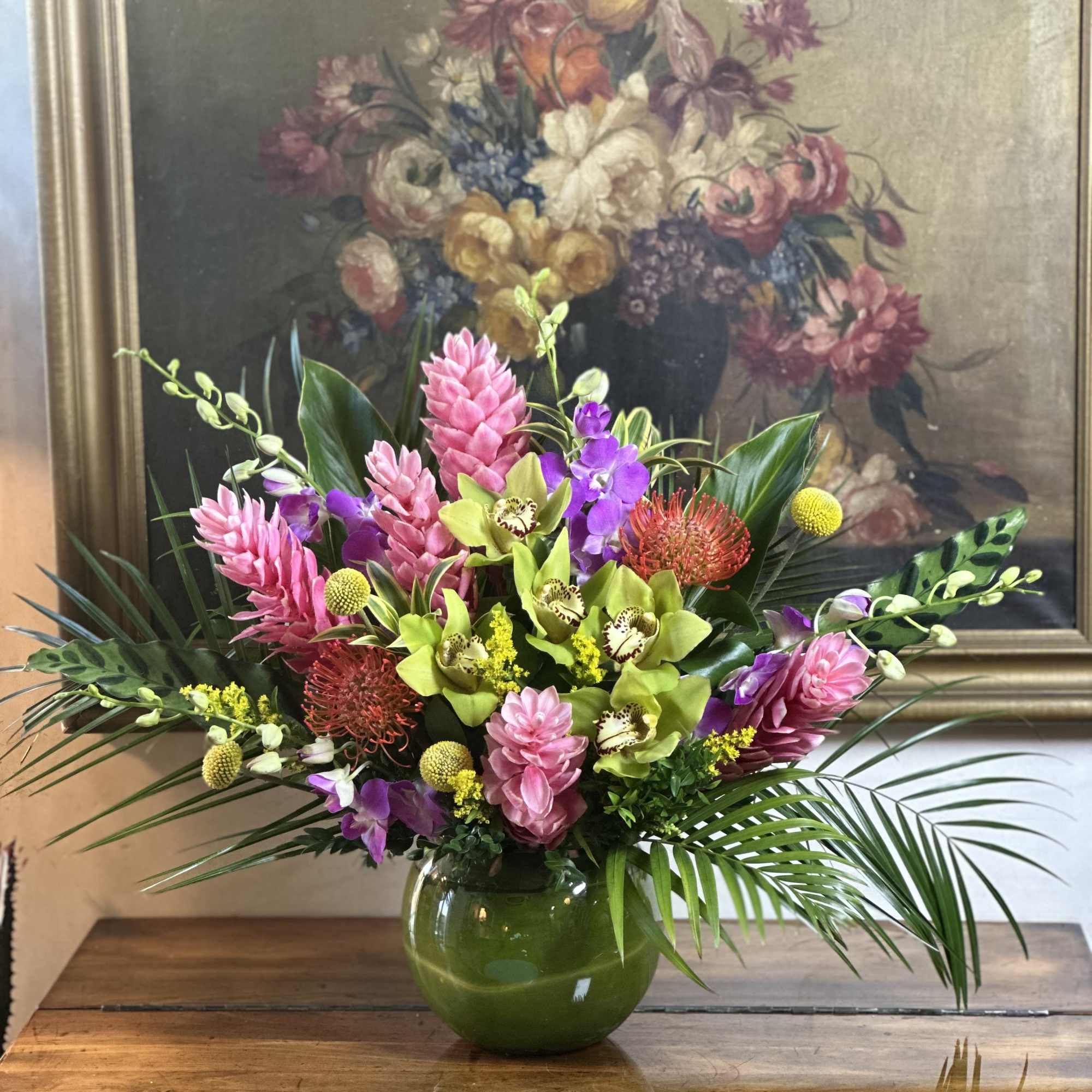 Tropical bouquet in a green glass vase with pink, purple, and green blooms