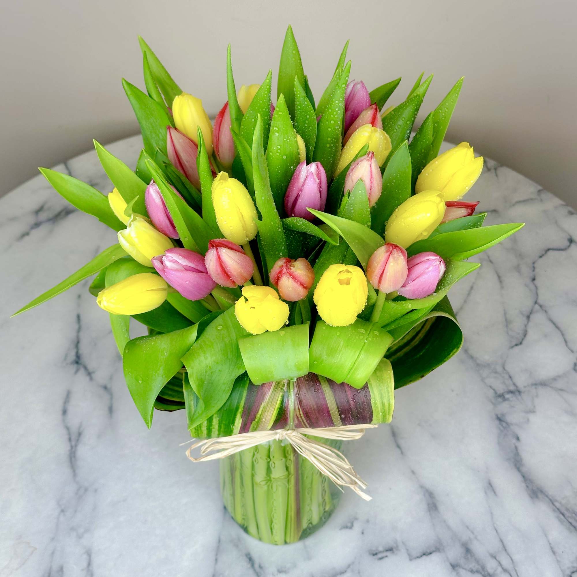 Bouquet of yellow and pink tulips in a clear glass vase