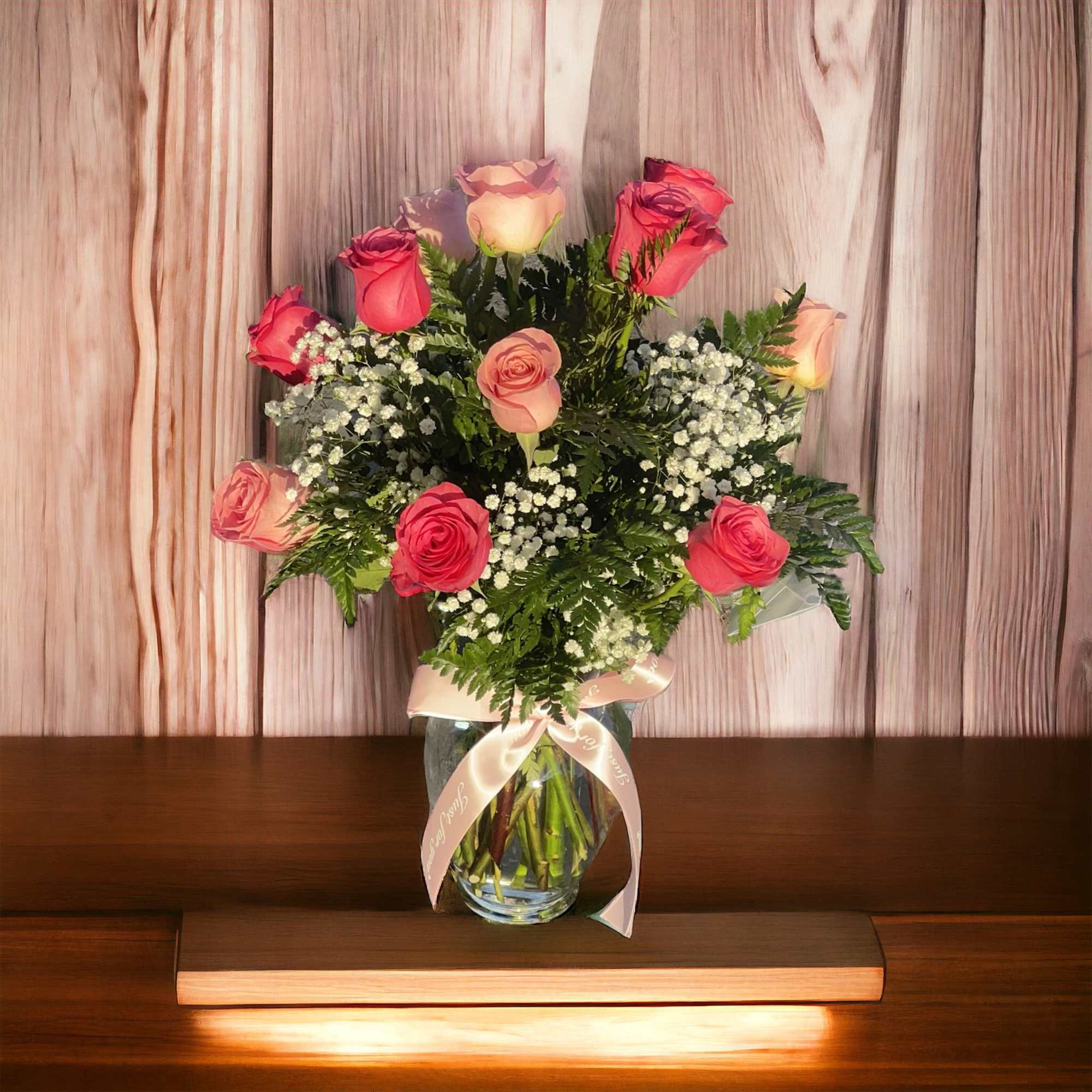 Bouquet of pink and peach roses in a glass vase with a ribbon