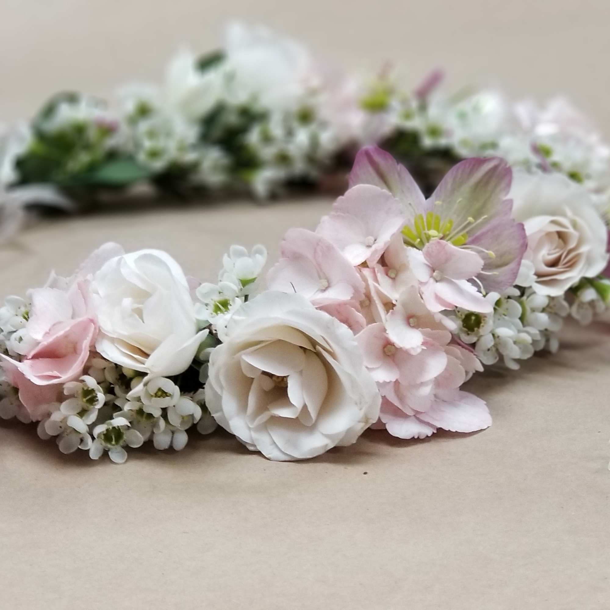 Floral crown with white and pink blossoms on a beige surface