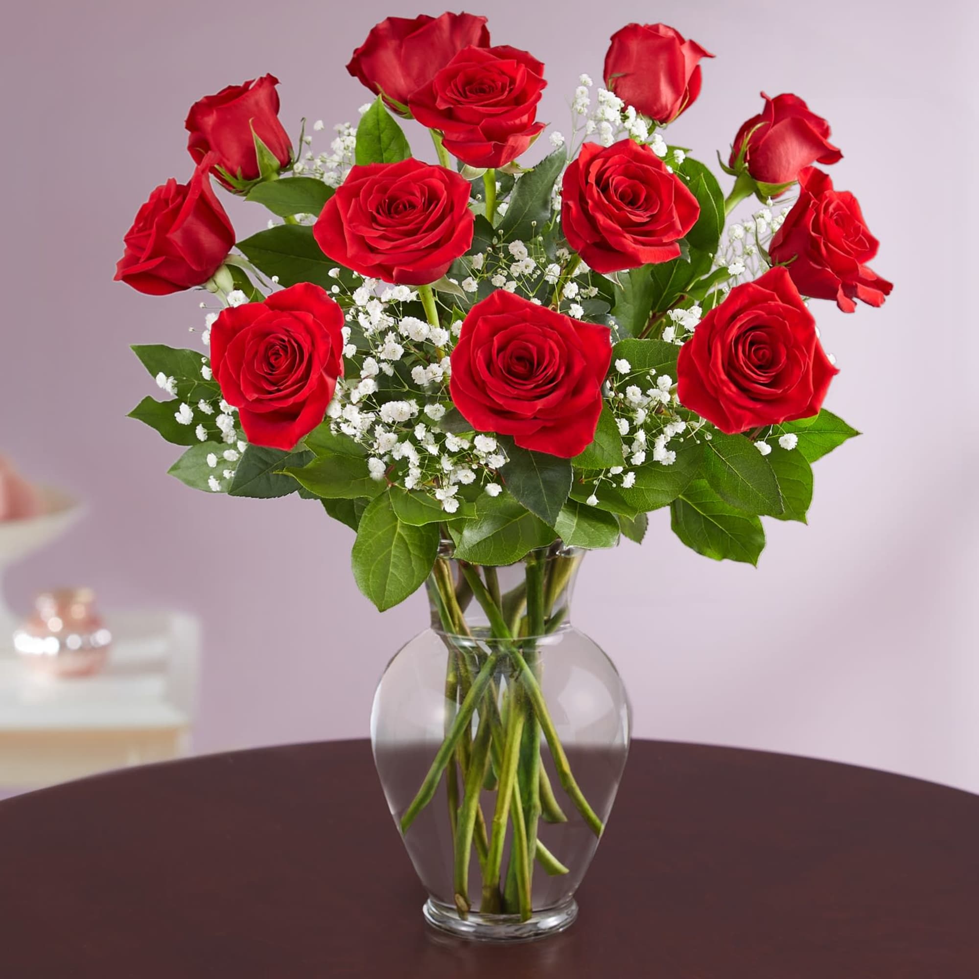 Red roses arranged in a clear glass vase with white baby's breath