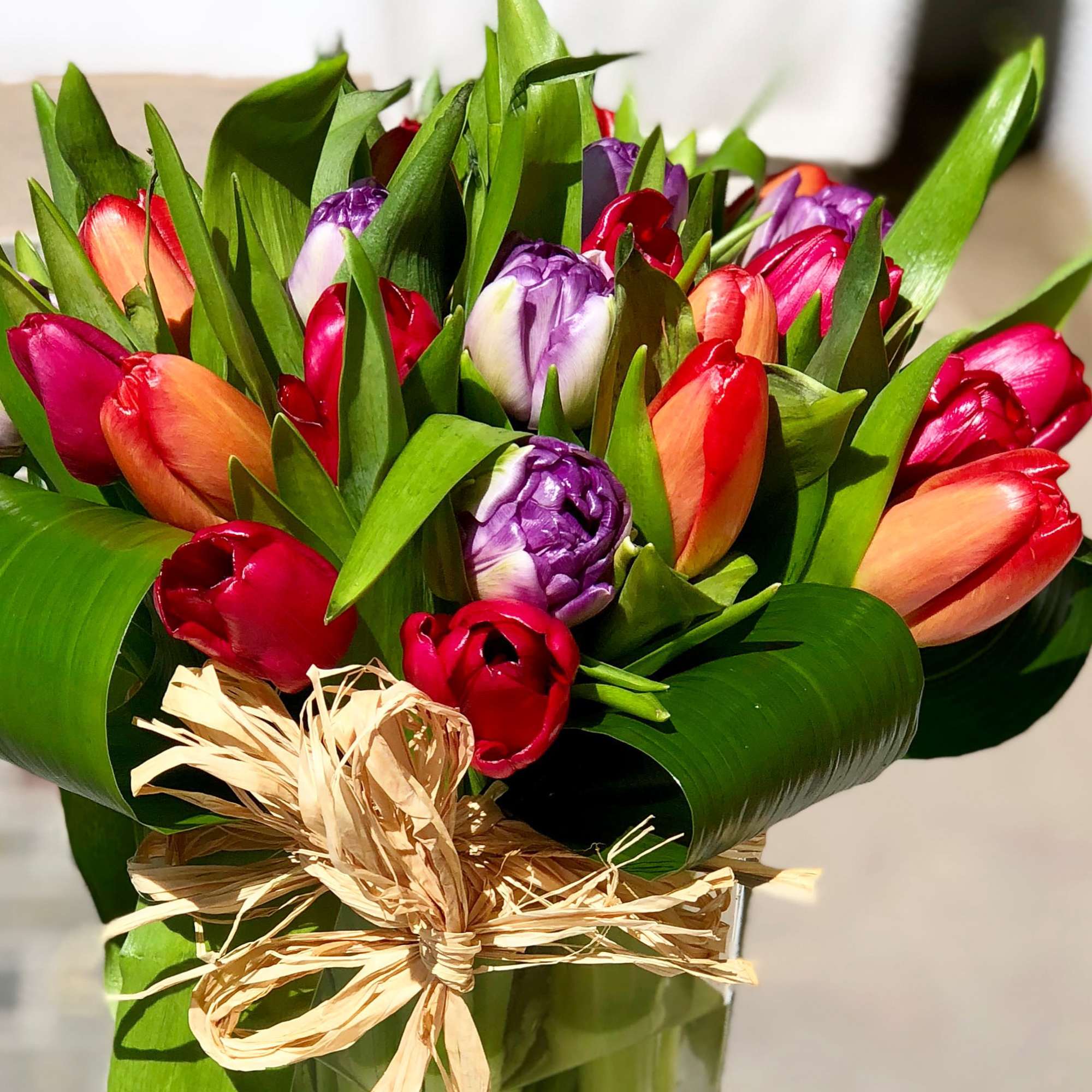 Bouquet of multicolored tulips wrapped with a raffia bow