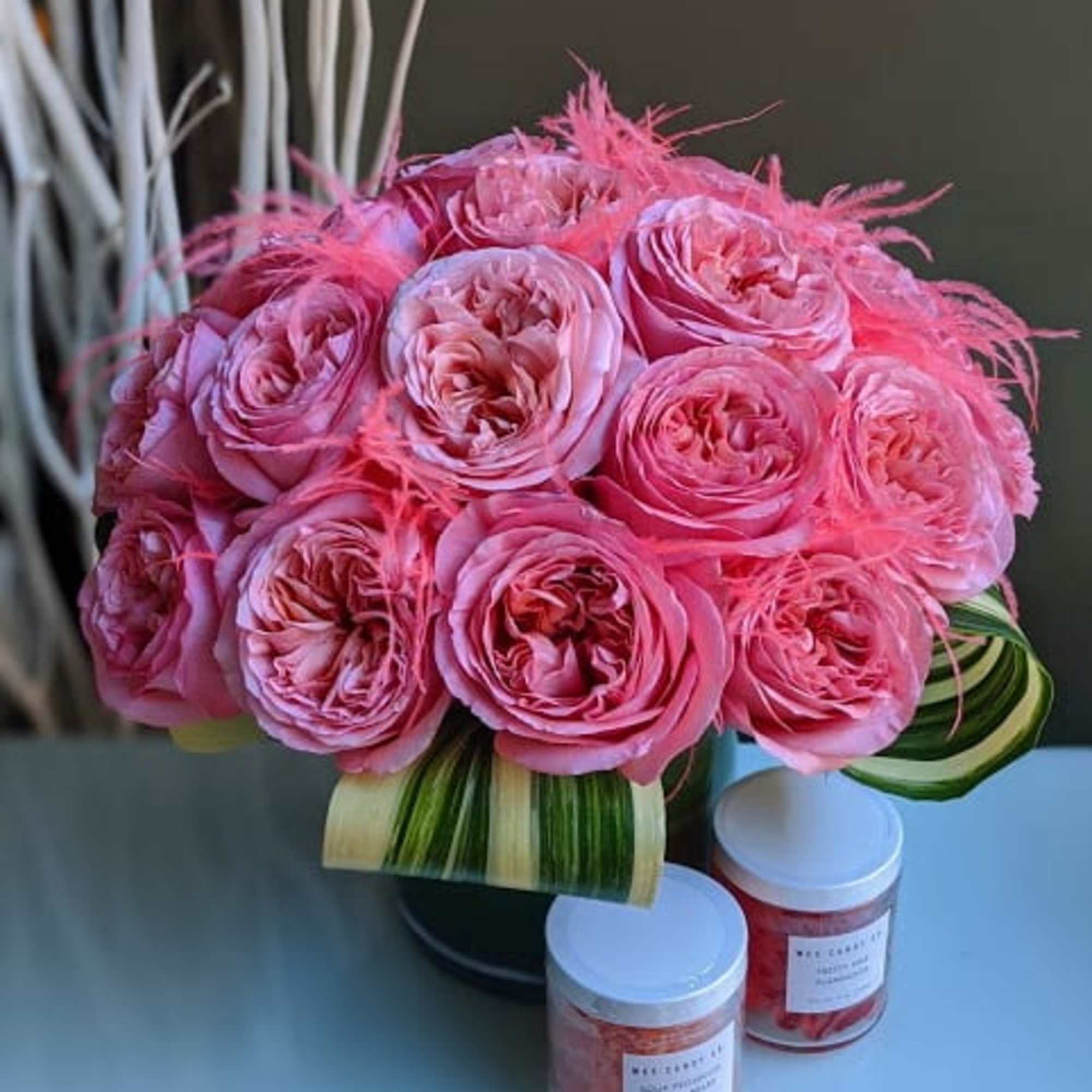 Pink rose bouquet with feather accents in a vase