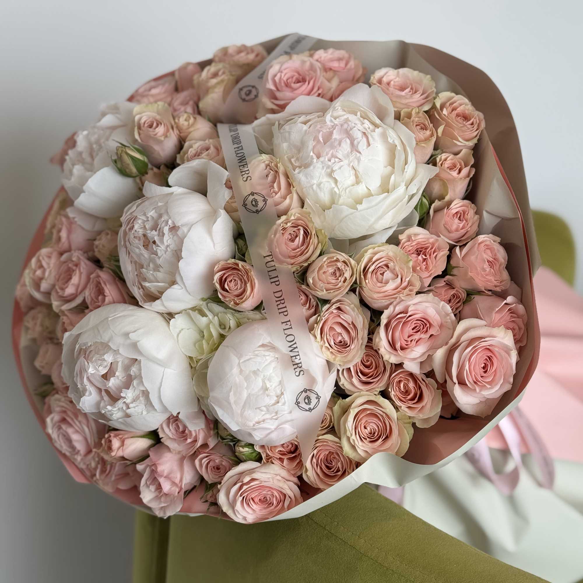 Bouquet of pale pink roses and white peonies wrapped in paper