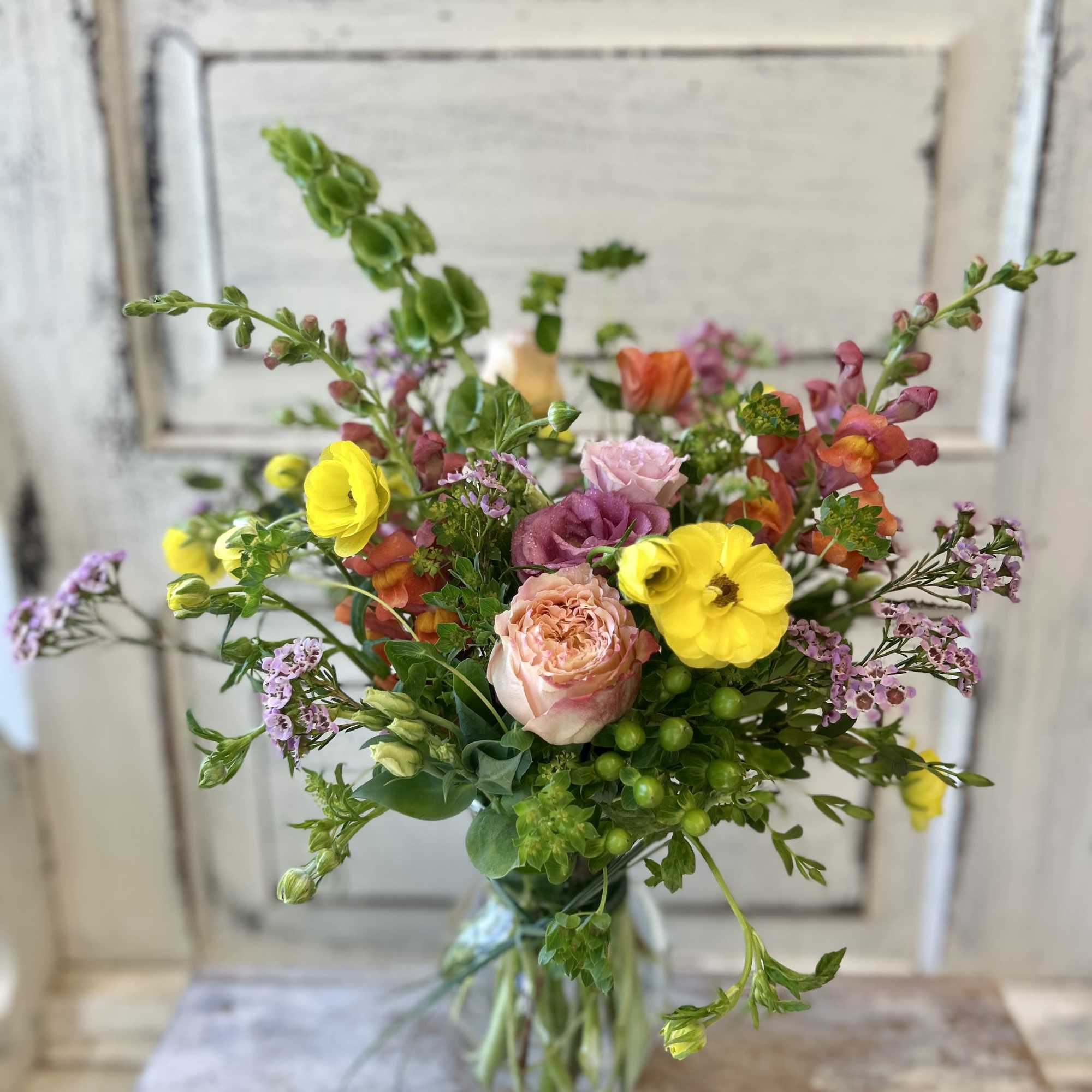 Mixed bouquet of yellow, pink, and purple flowers in a clear glass vase