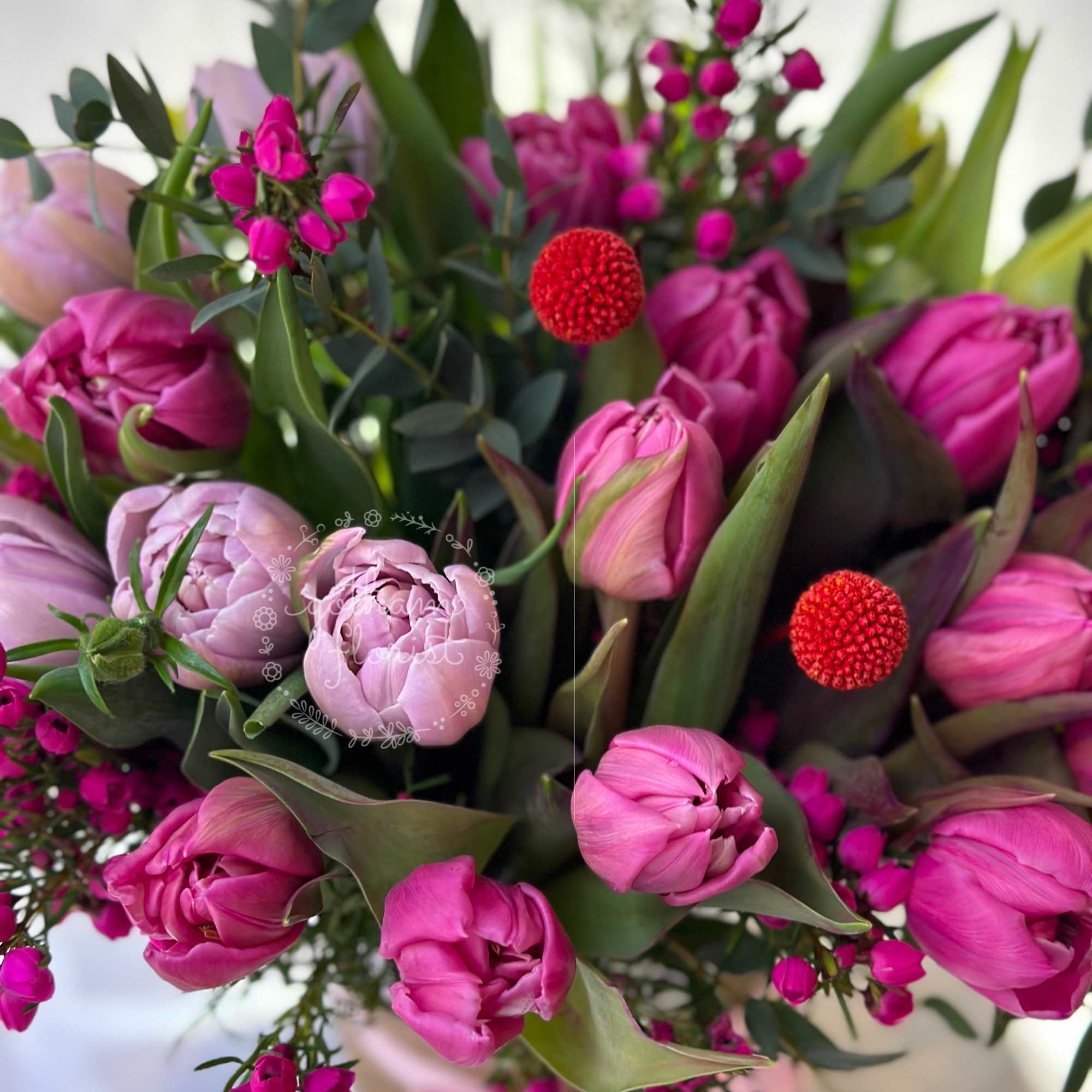 Pink tulips and pale peonies in a mixed bouquet with red berry accents