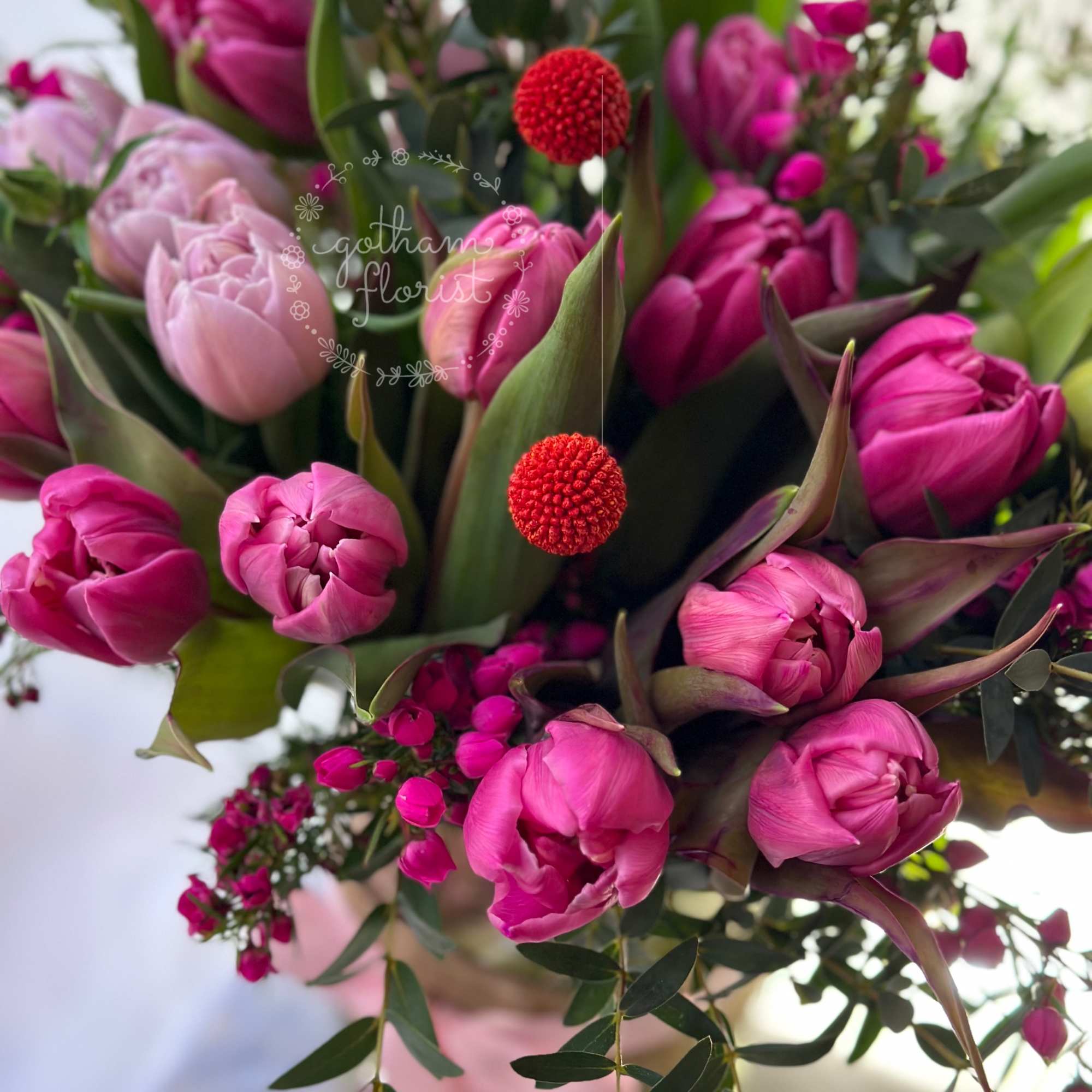 Pink tulips and red berry-like accents in a bouquet