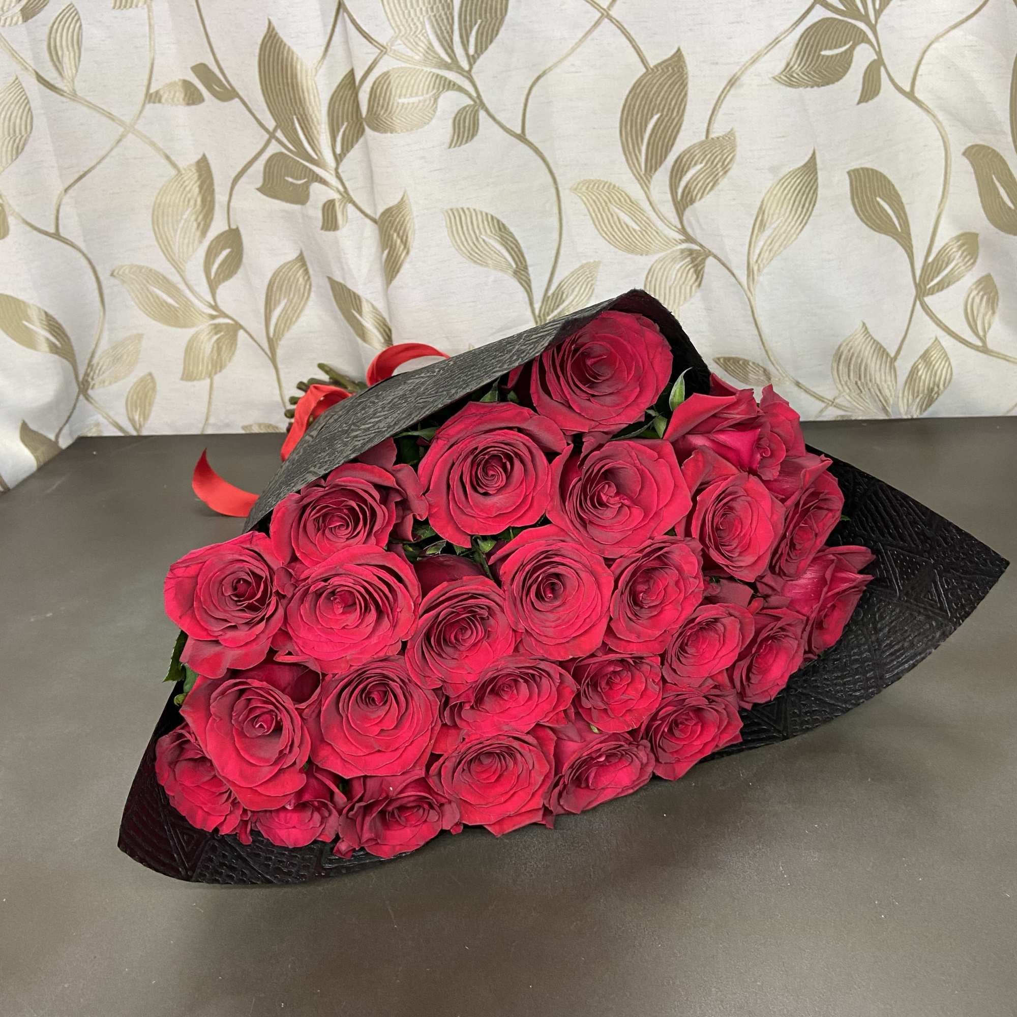 Bouquet of bright pink roses wrapped in black paper