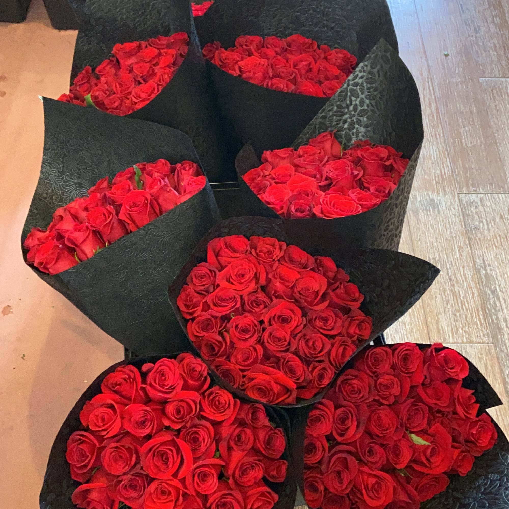 Bundles of red roses wrapped in black paper