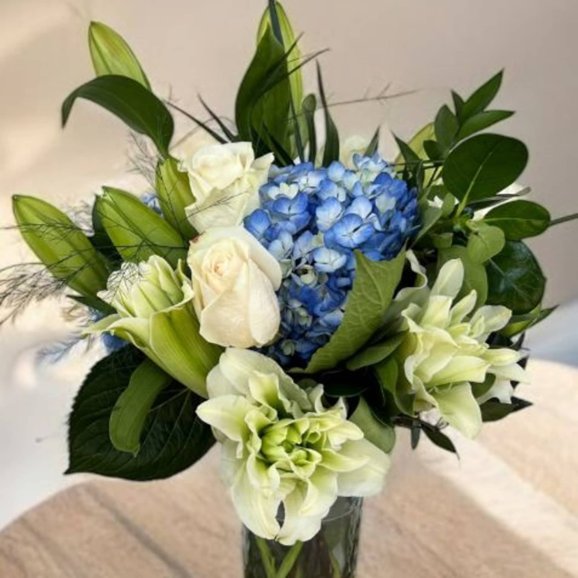 Blue hydrangeas and white roses in a clear glass vase