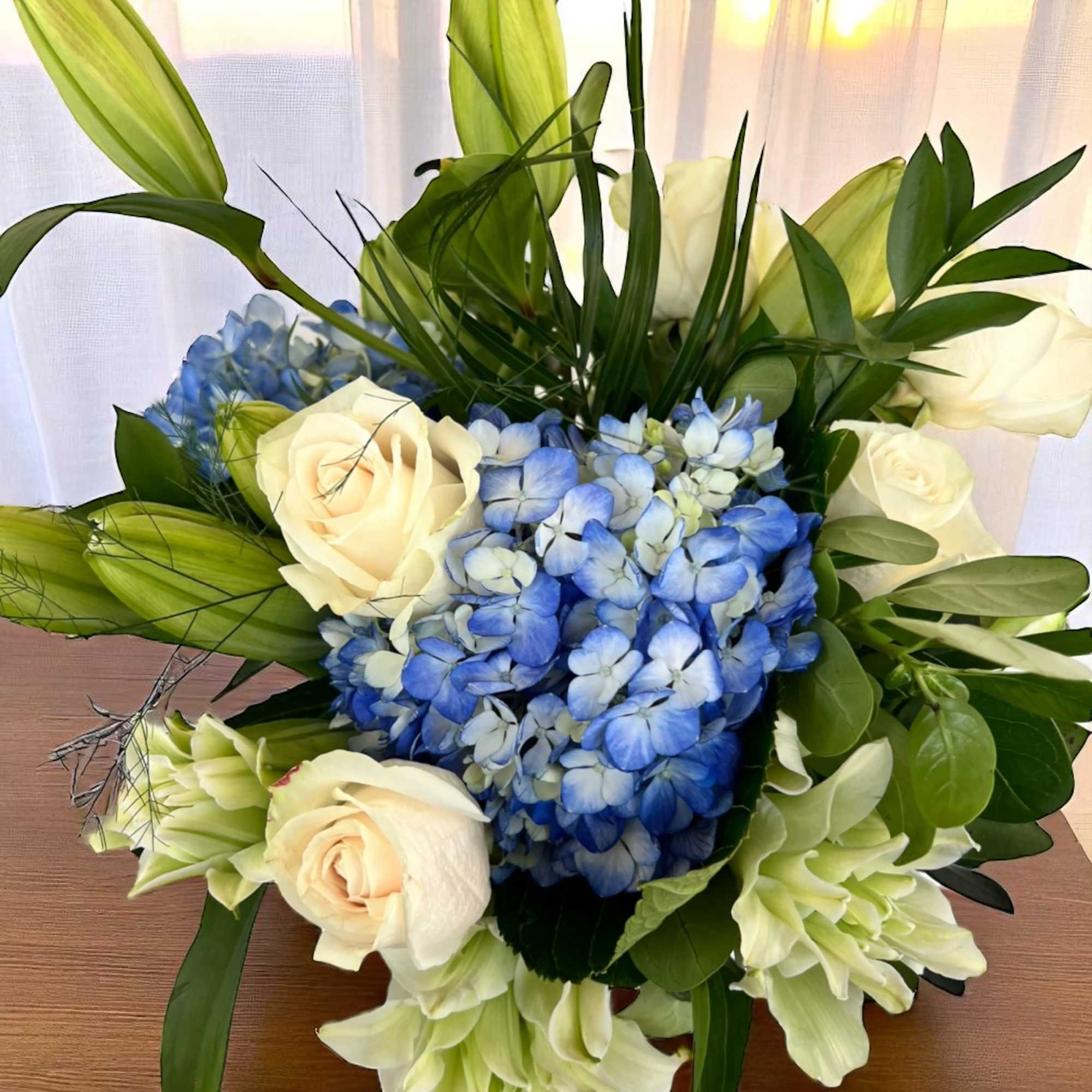 Blue hydrangeas with cream roses and white lilies in a bouquet