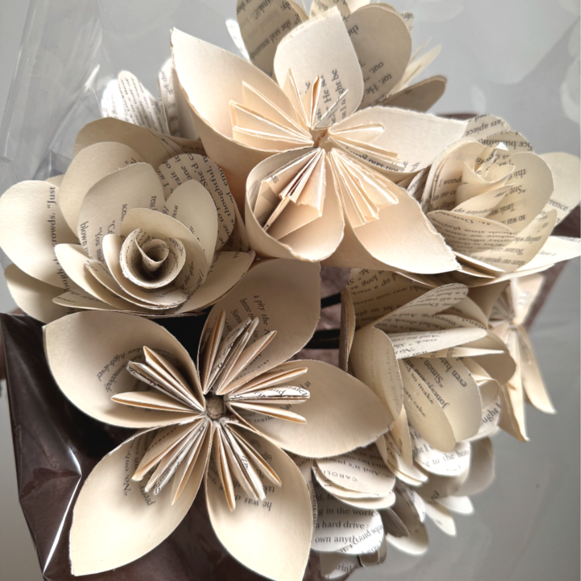 Bouquet of cream and printed paper origami flowers wrapped in brown and clear cellophane.