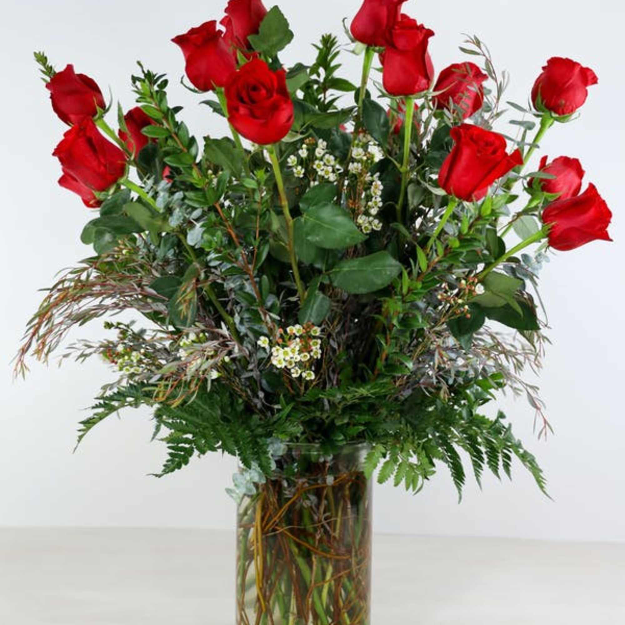 Tall bouquet of red roses in a clear glass vase