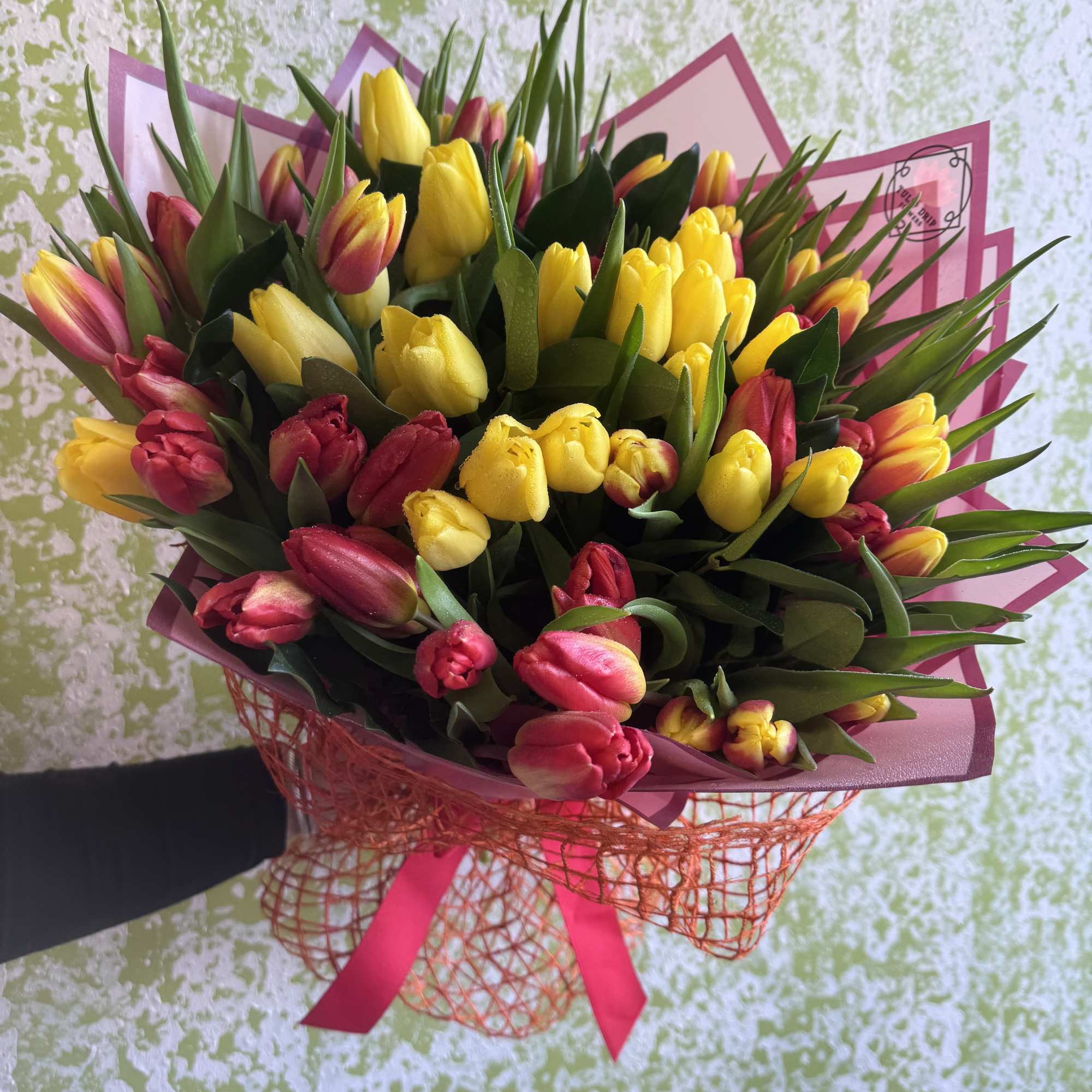 Bouquet of yellow and pink tulips wrapped in pink paper