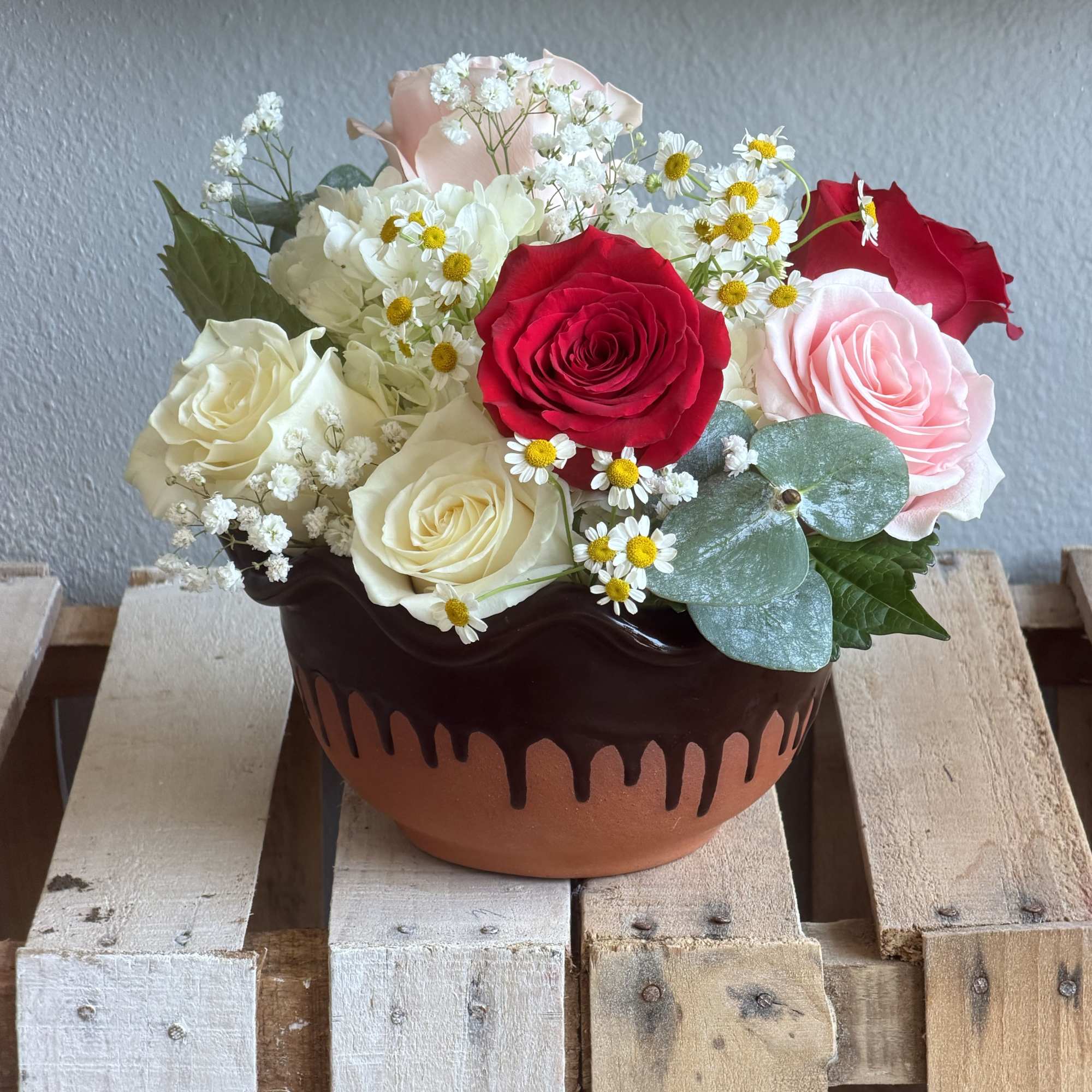 A compact cluster of red, blush pink and creamy white roses makes