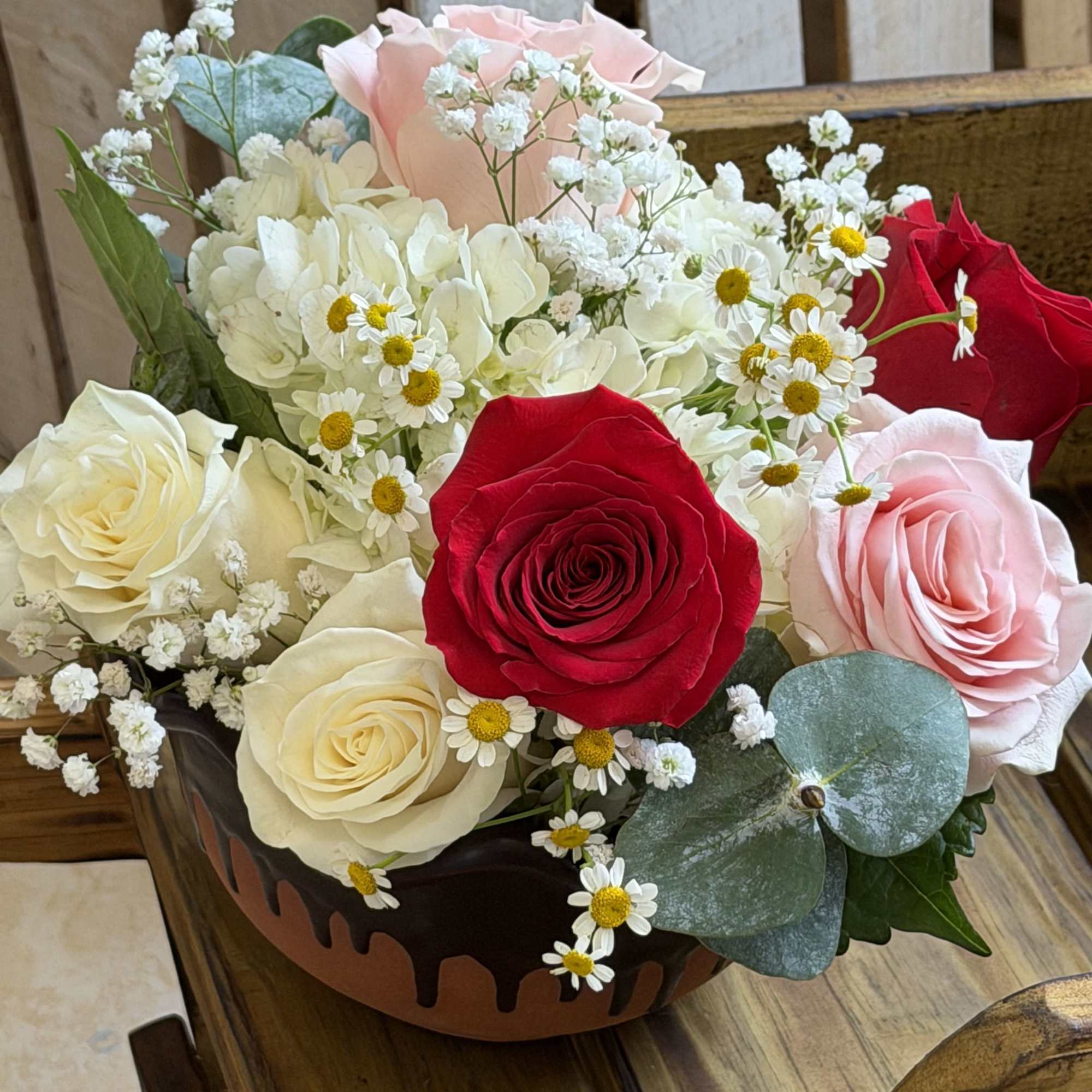 A compact cluster of red, blush pink and creamy white roses makes