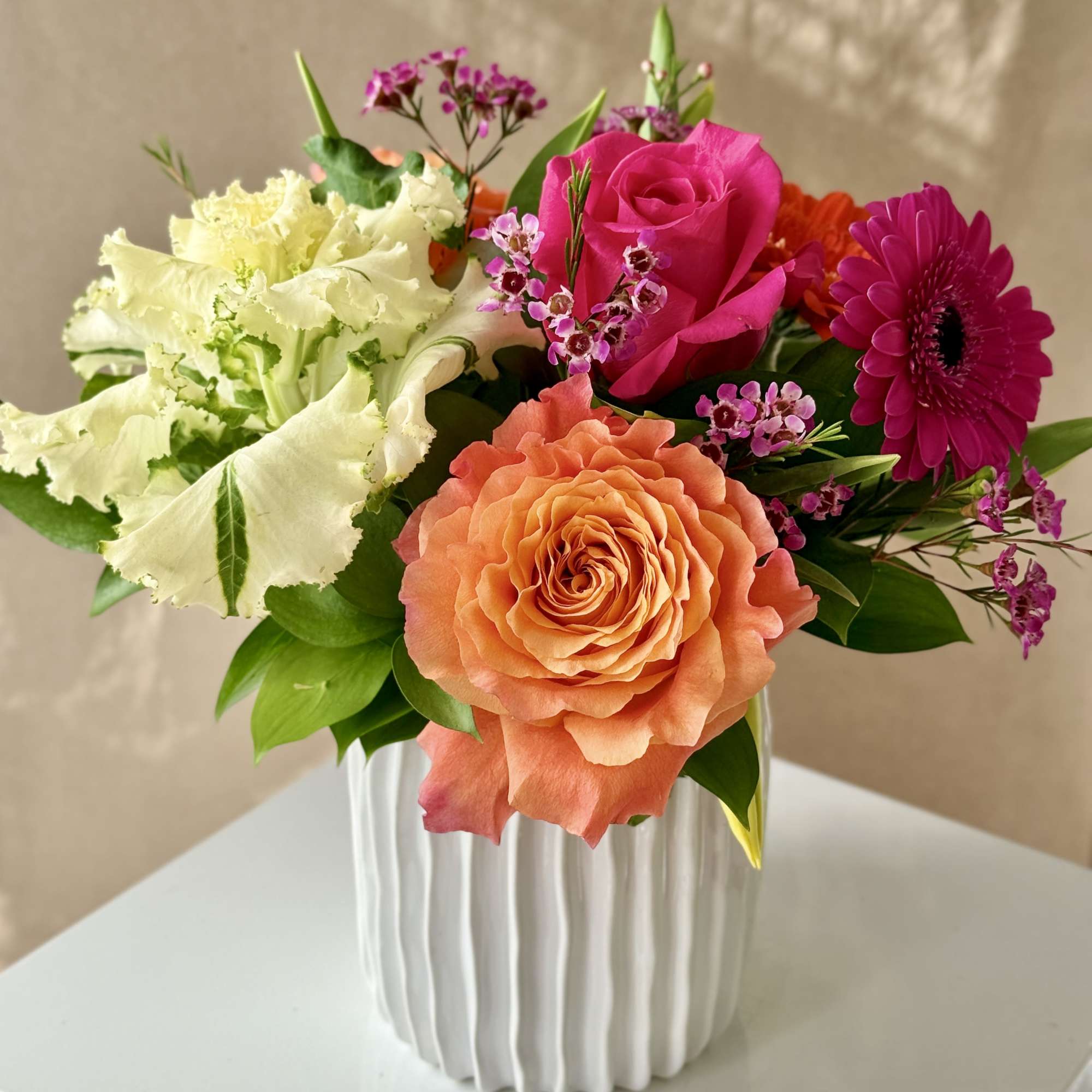 Spring with Tulips, Kale, Roses and Gerbera Daisies arranged in a ceramic