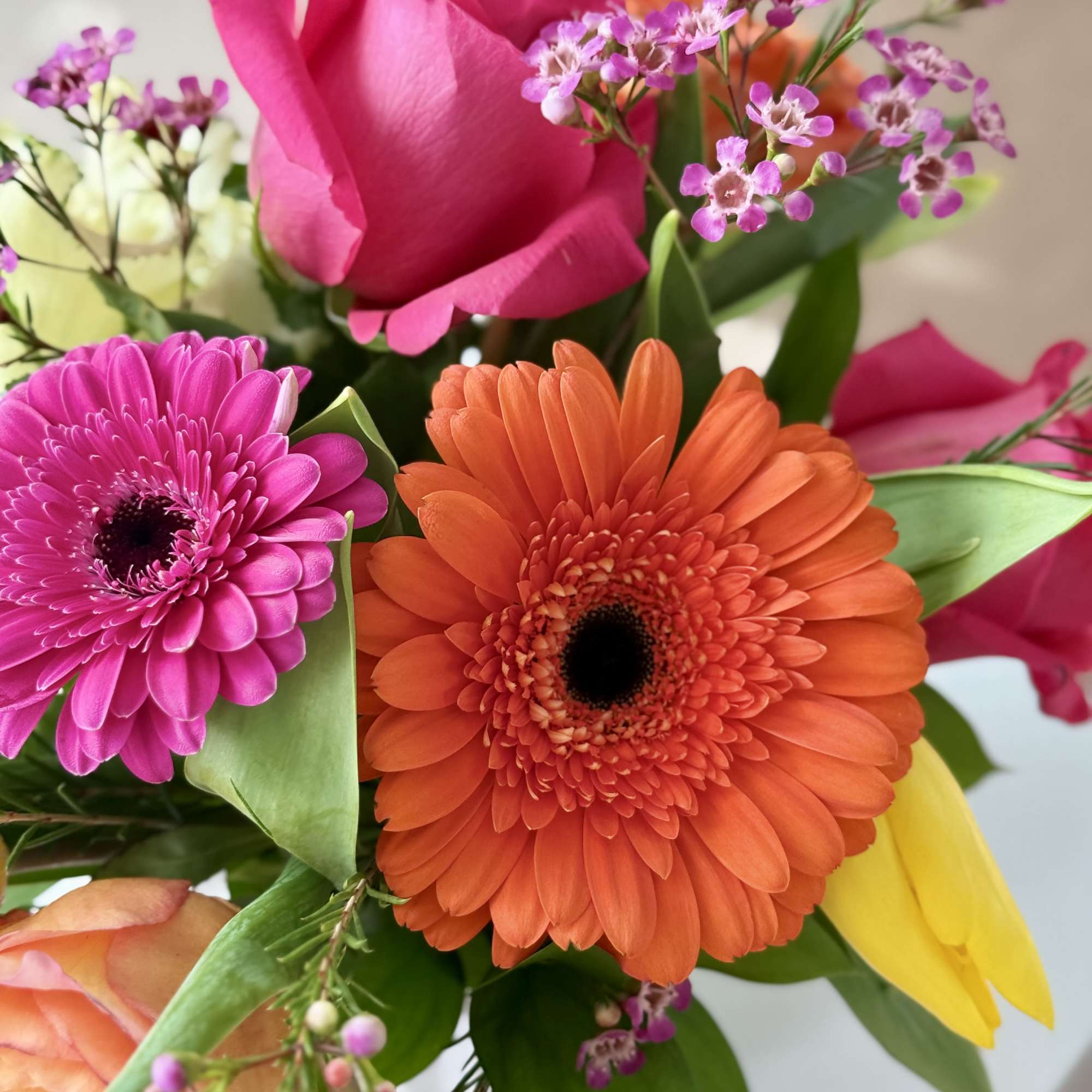 Bouquet of pink and orange gerbera daisies with roses and small purple flowers