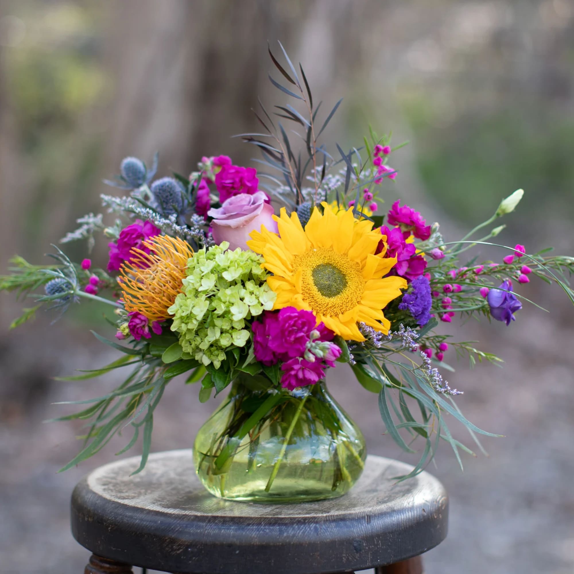 Colorful bouquet in a round glass vase with a large yellow sunflower