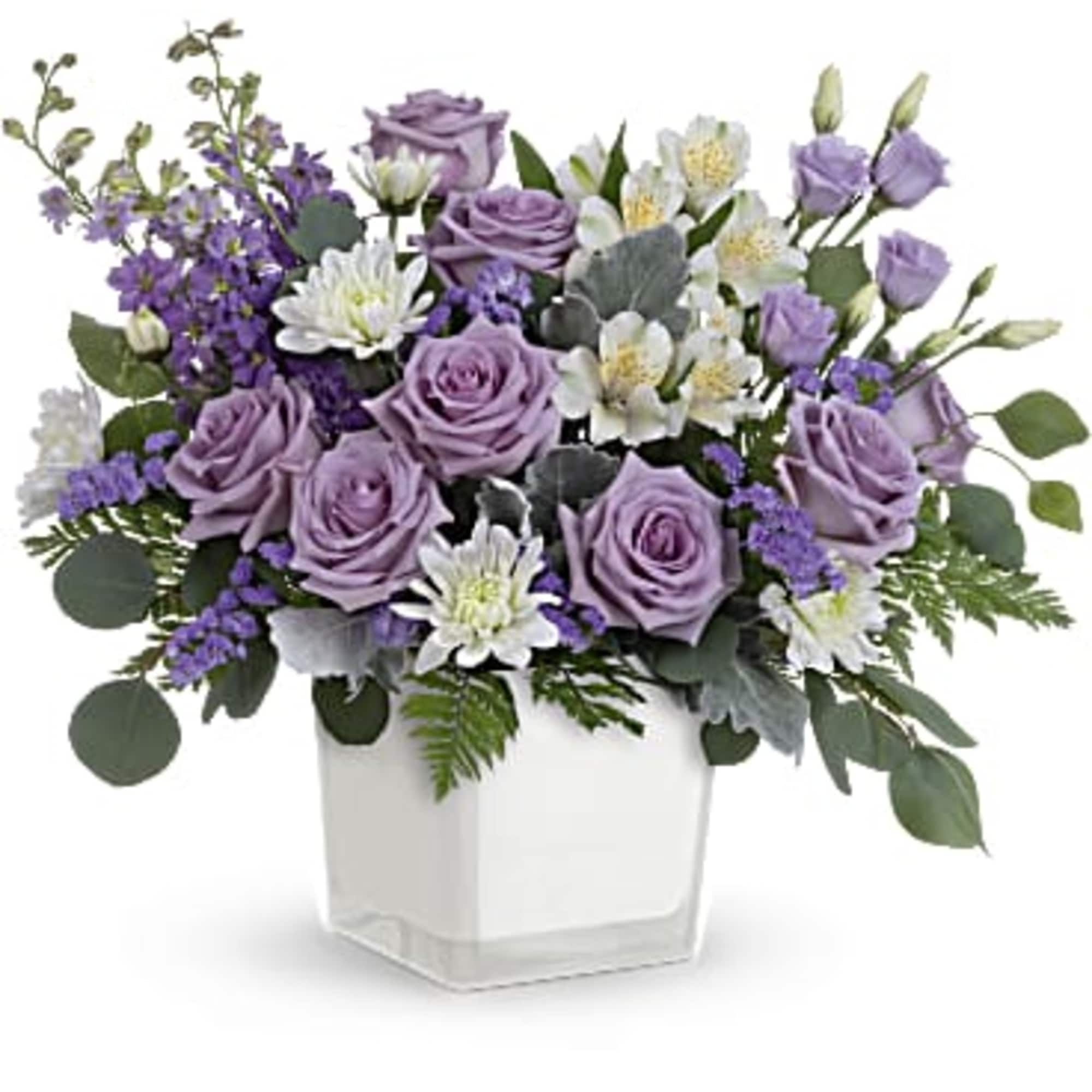 Lavender roses and white flowers in a clear square vase