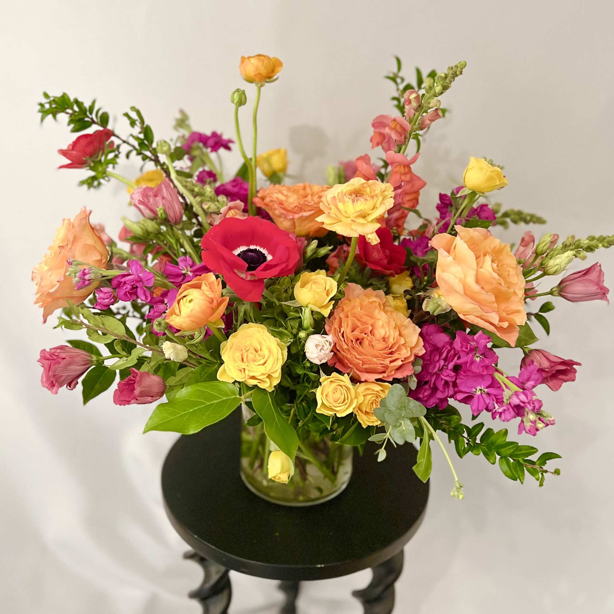 Bright mixed bouquet in a glass vase with pink, orange, and yellow blooms